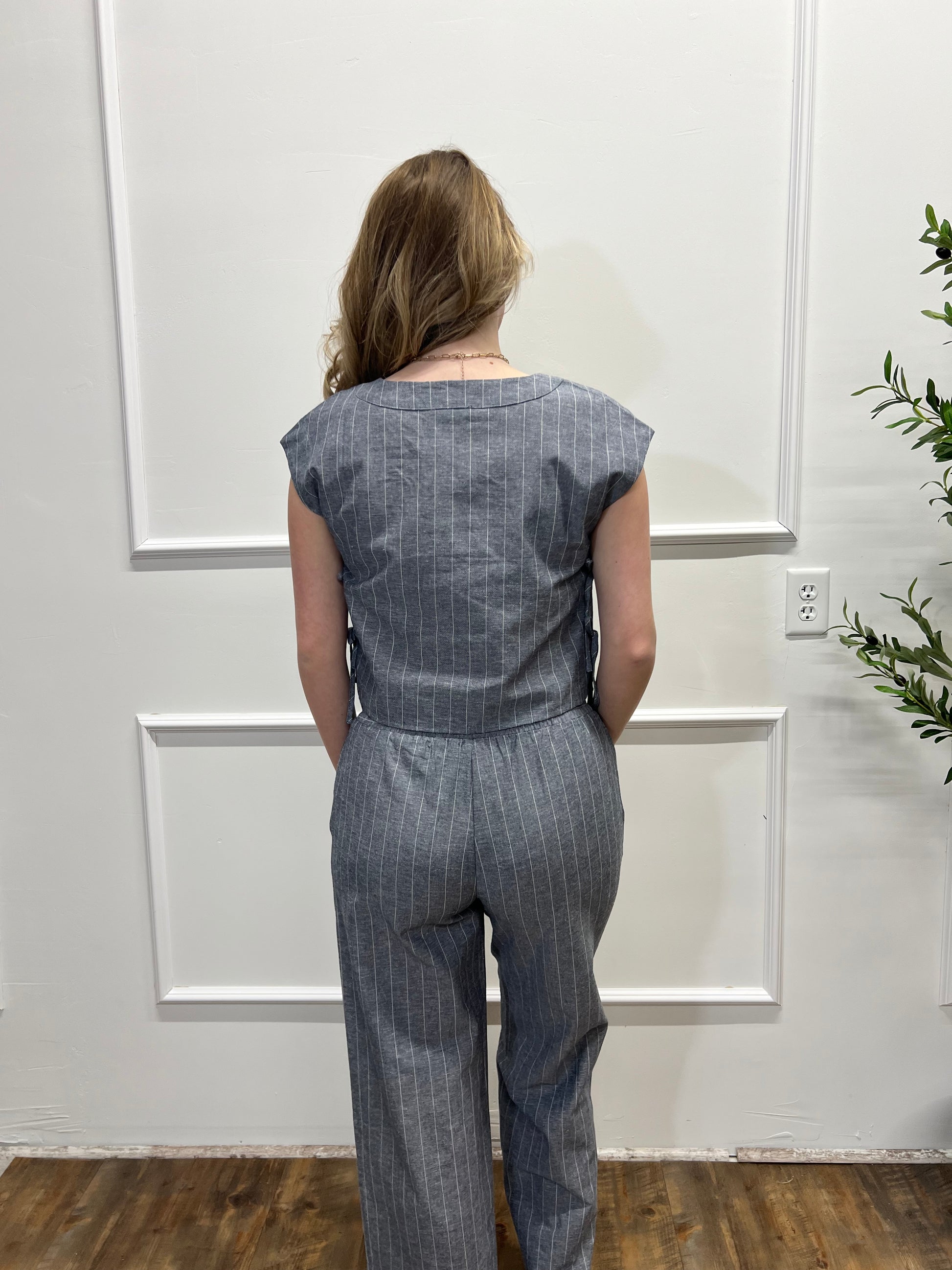 Person wearing a blue denim outfit standing in front of a white door.