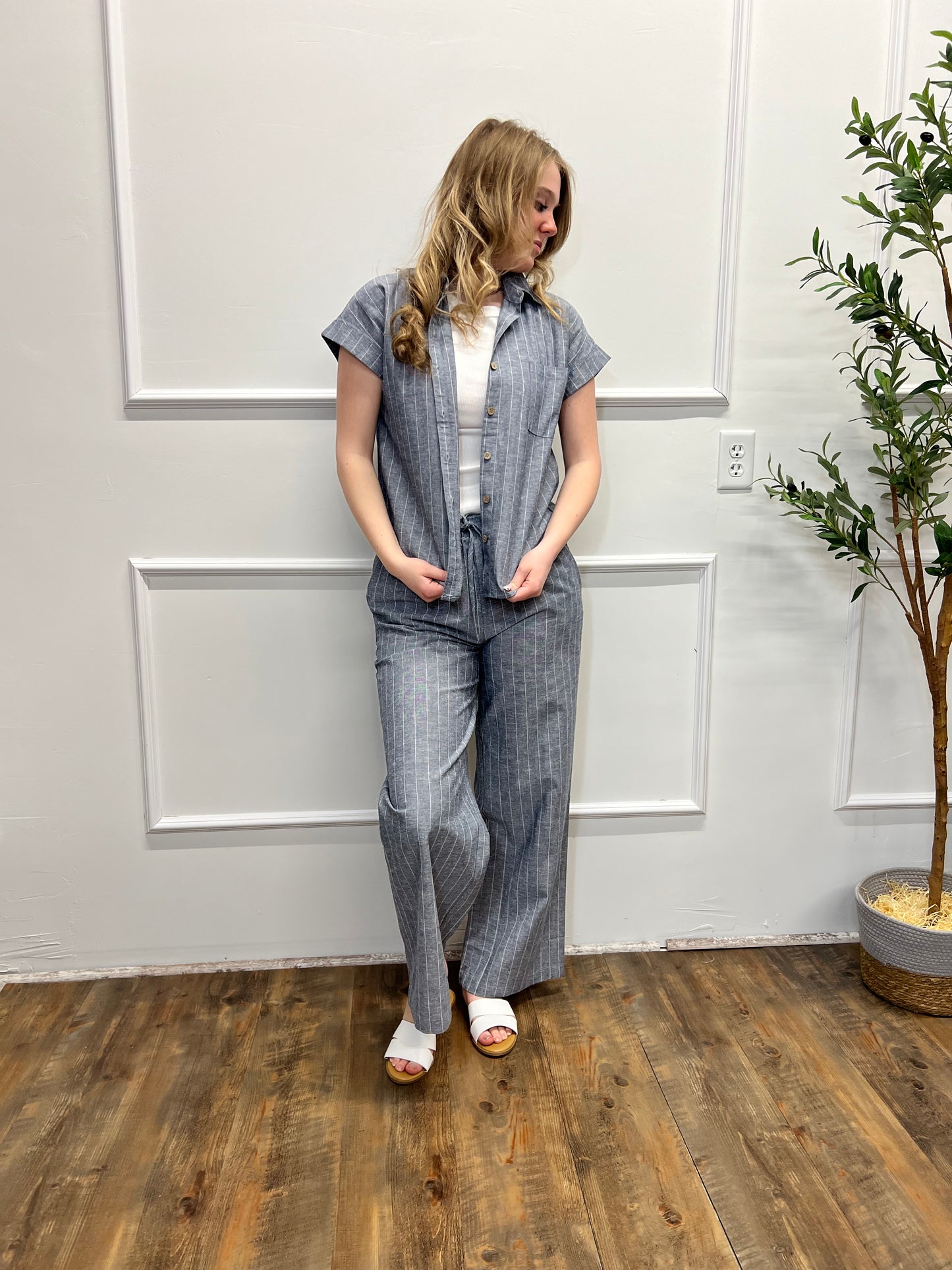 Person wearing a denim dress standing in a room with white walls and wooden flooring.