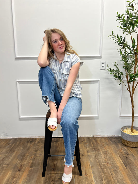 Person sitting on a stool in a room with white walls and wooden flooring.