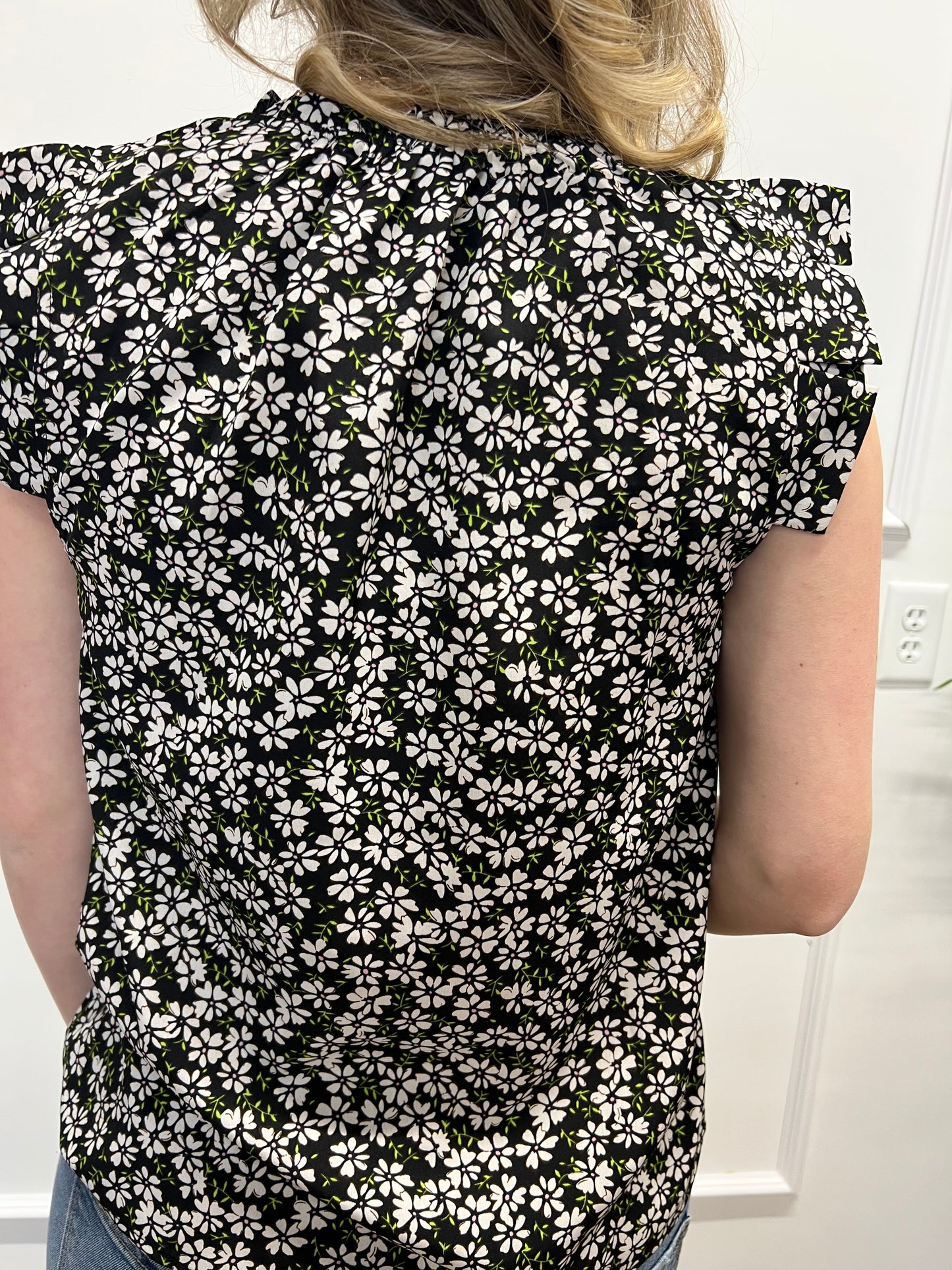 Person wearing a black and white floral dress with a plain background