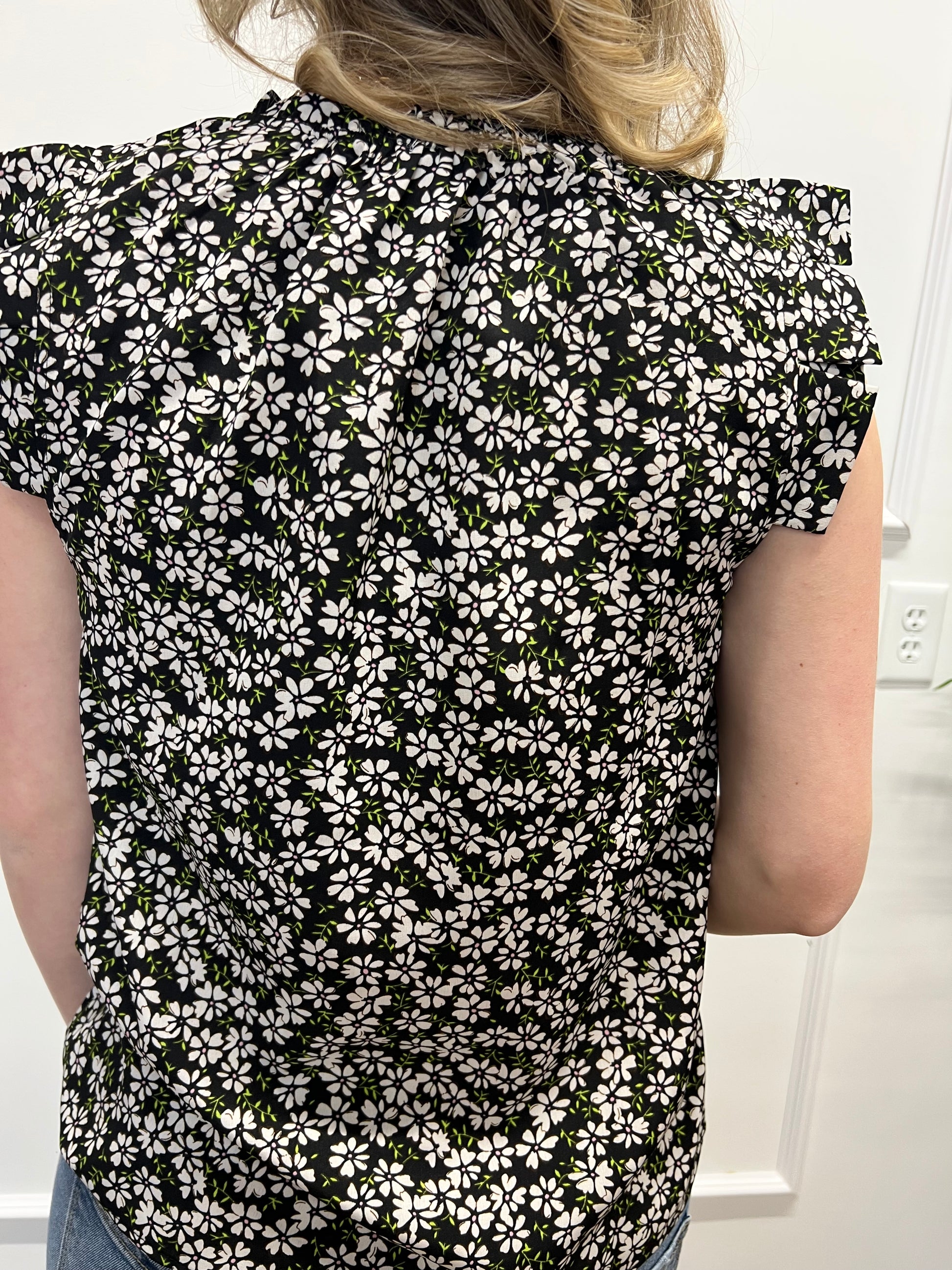 Person wearing a black and white floral dress with a plain background