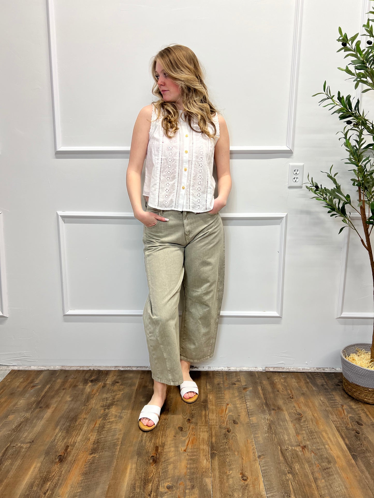 Person standing in a room with white paneled walls and wooden flooring.