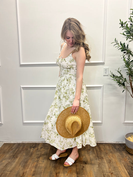 Woman holding a straw hat in a room with wooden floor and white walls.