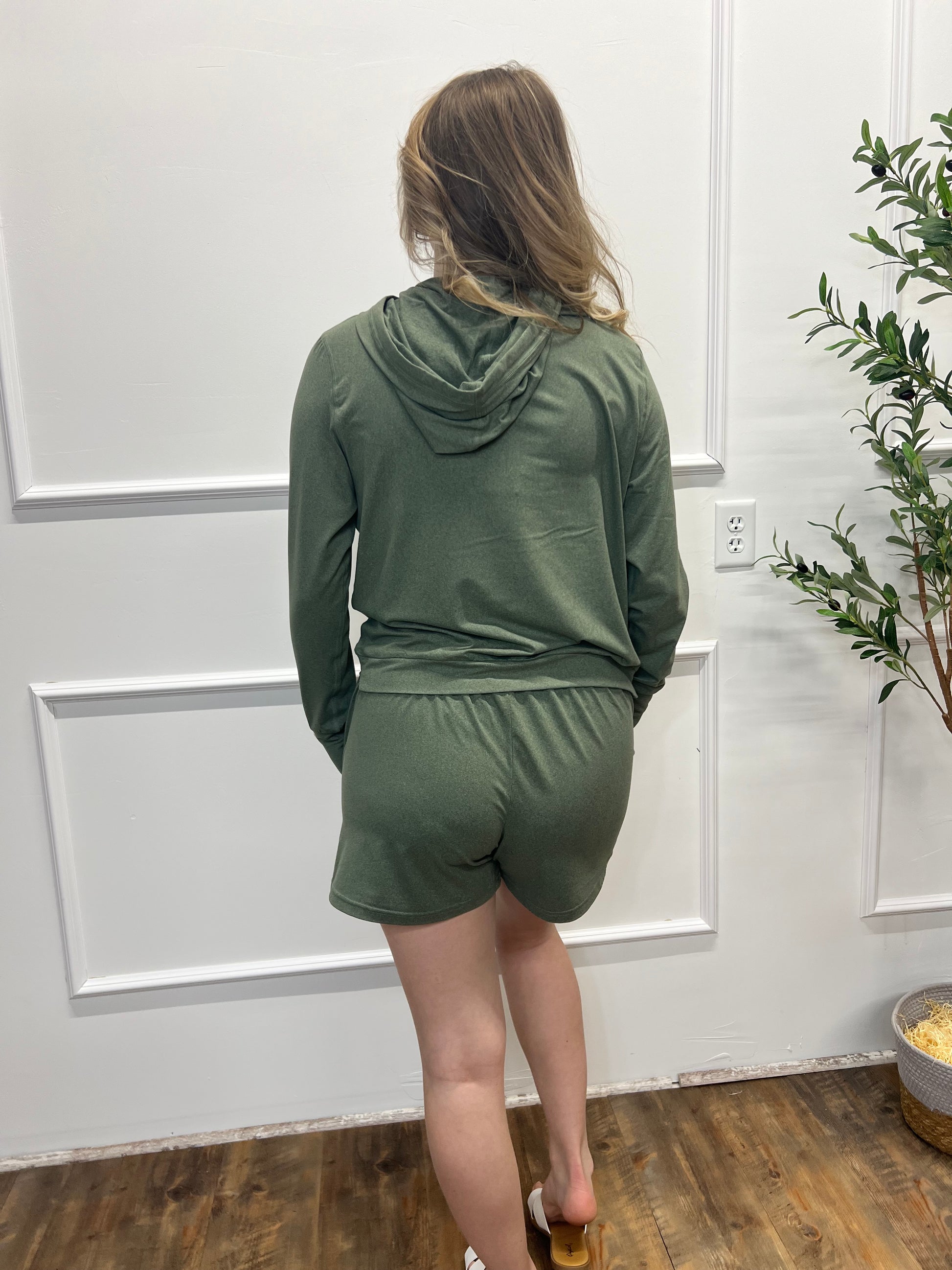 Person wearing a green jacket standing in front of a white door.