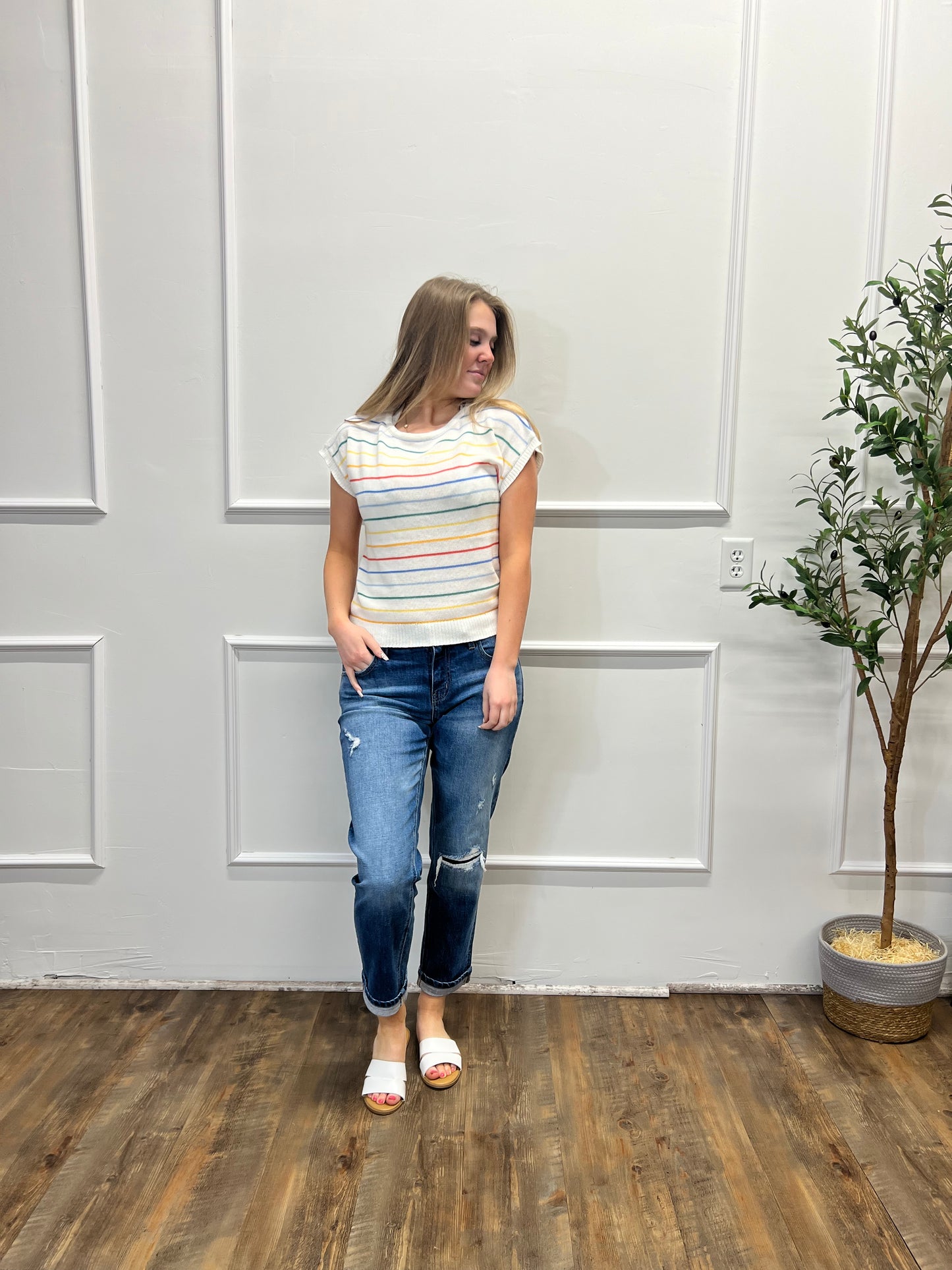 Person standing in a room with a white door and wooden floor.