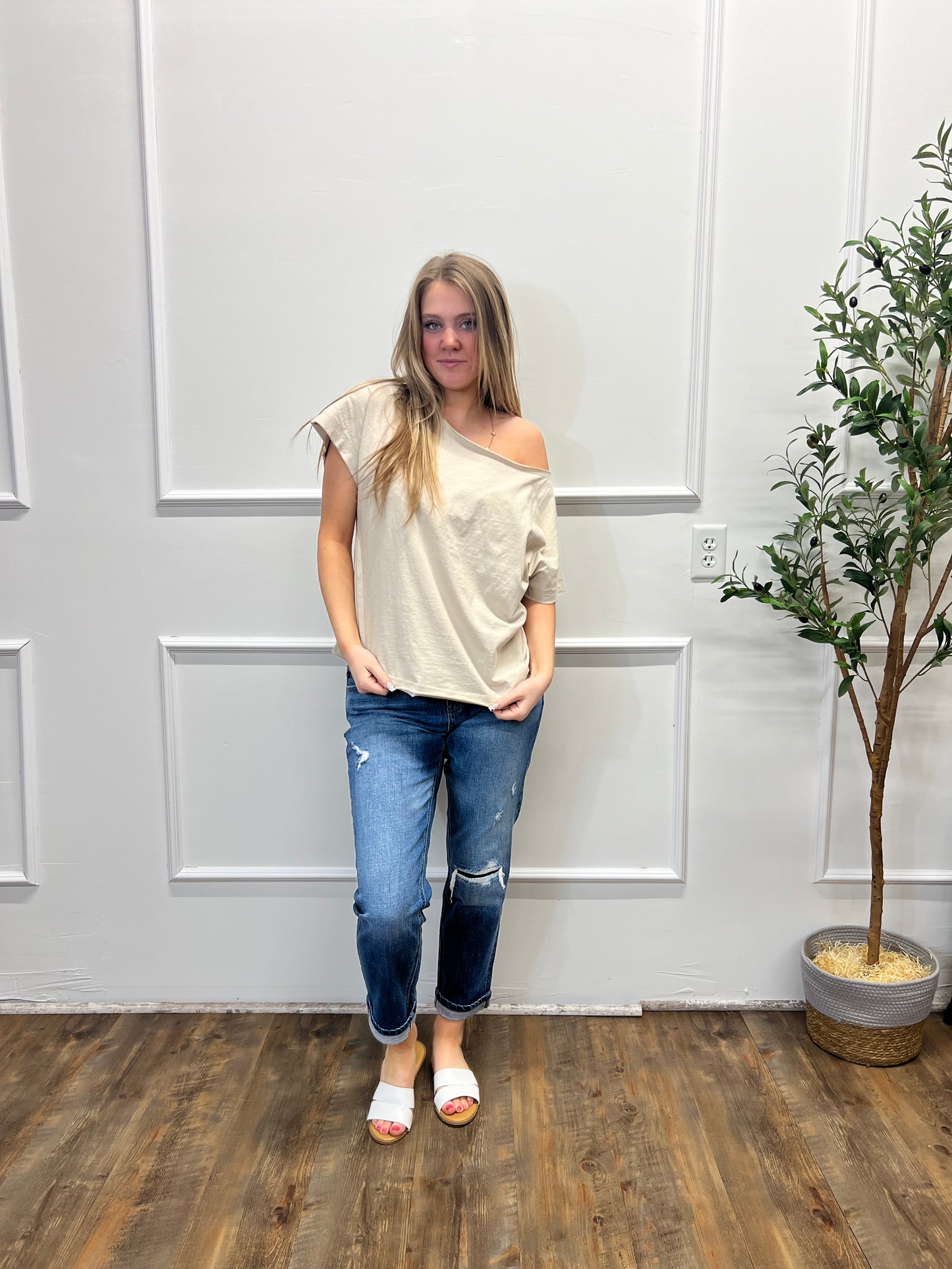 Person standing in a room with white paneled walls and a wooden floor.