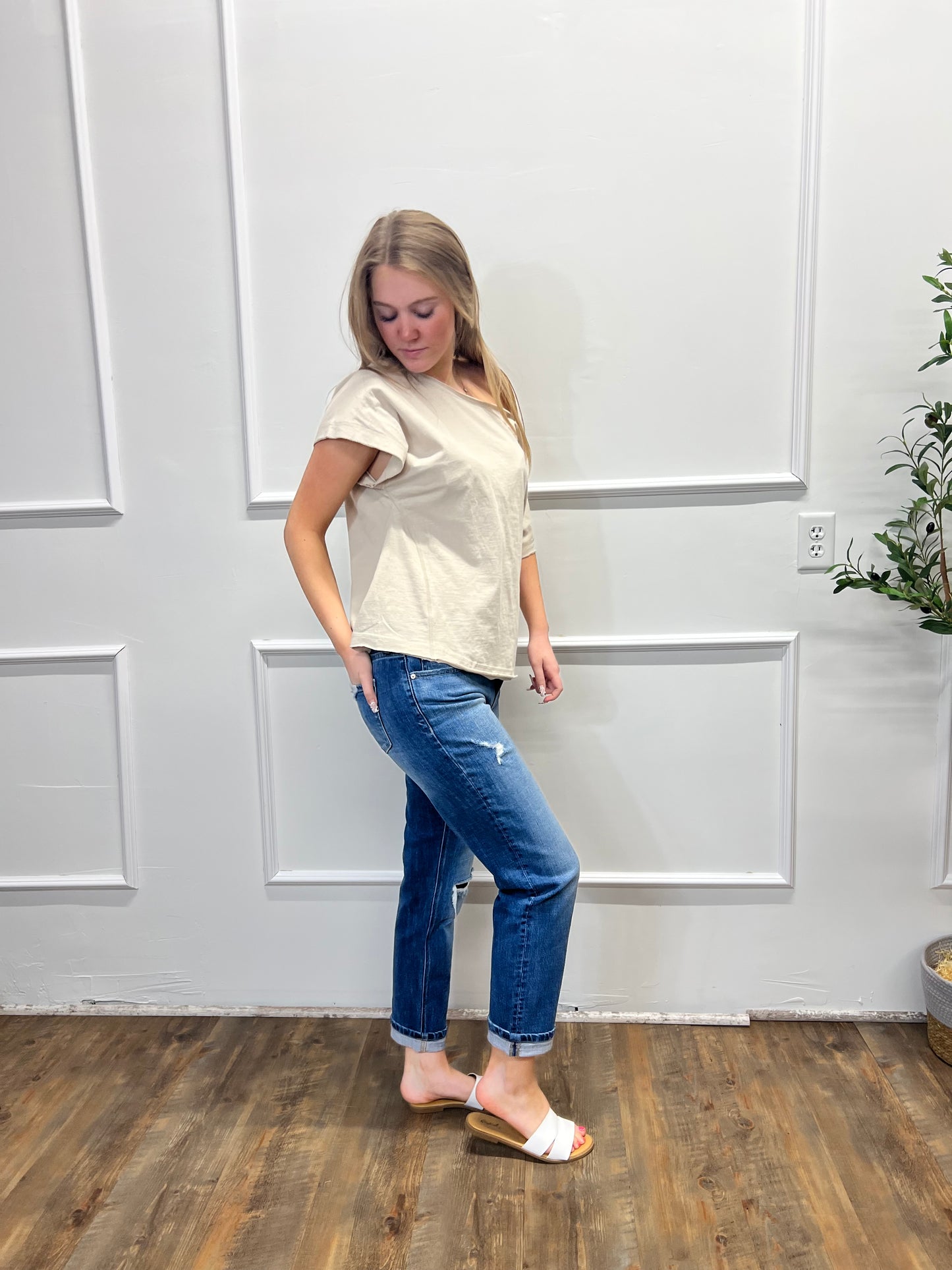 Person holding a white bag in a room with wooden flooring and white walls.
