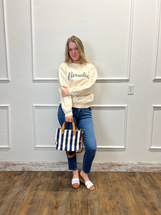 Person wearing a hoodie and jeans standing in front of a white paneled wall.