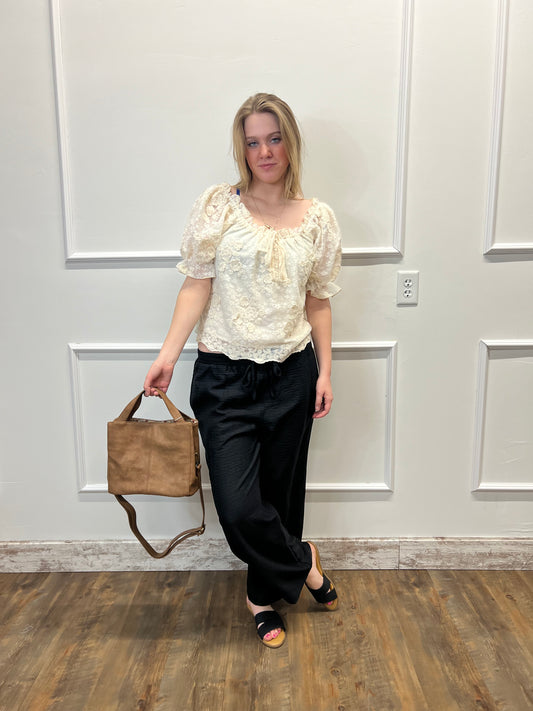 Woman holding a brown handbag in front of a white door.