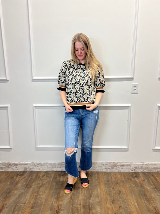 Woman standing in a room with wooden flooring and white walls.