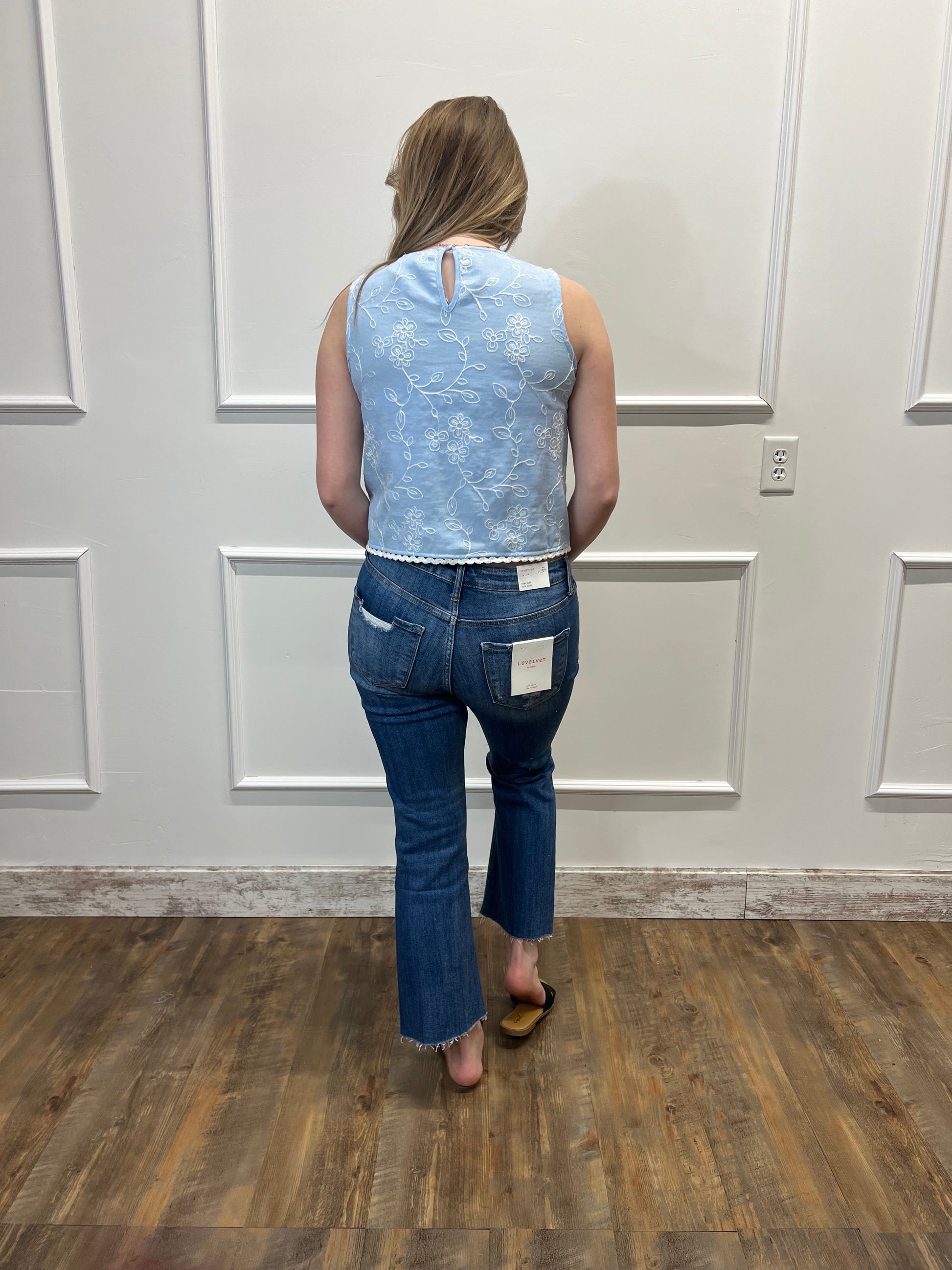 Person wearing a blue denim outfit standing in front of a white door.