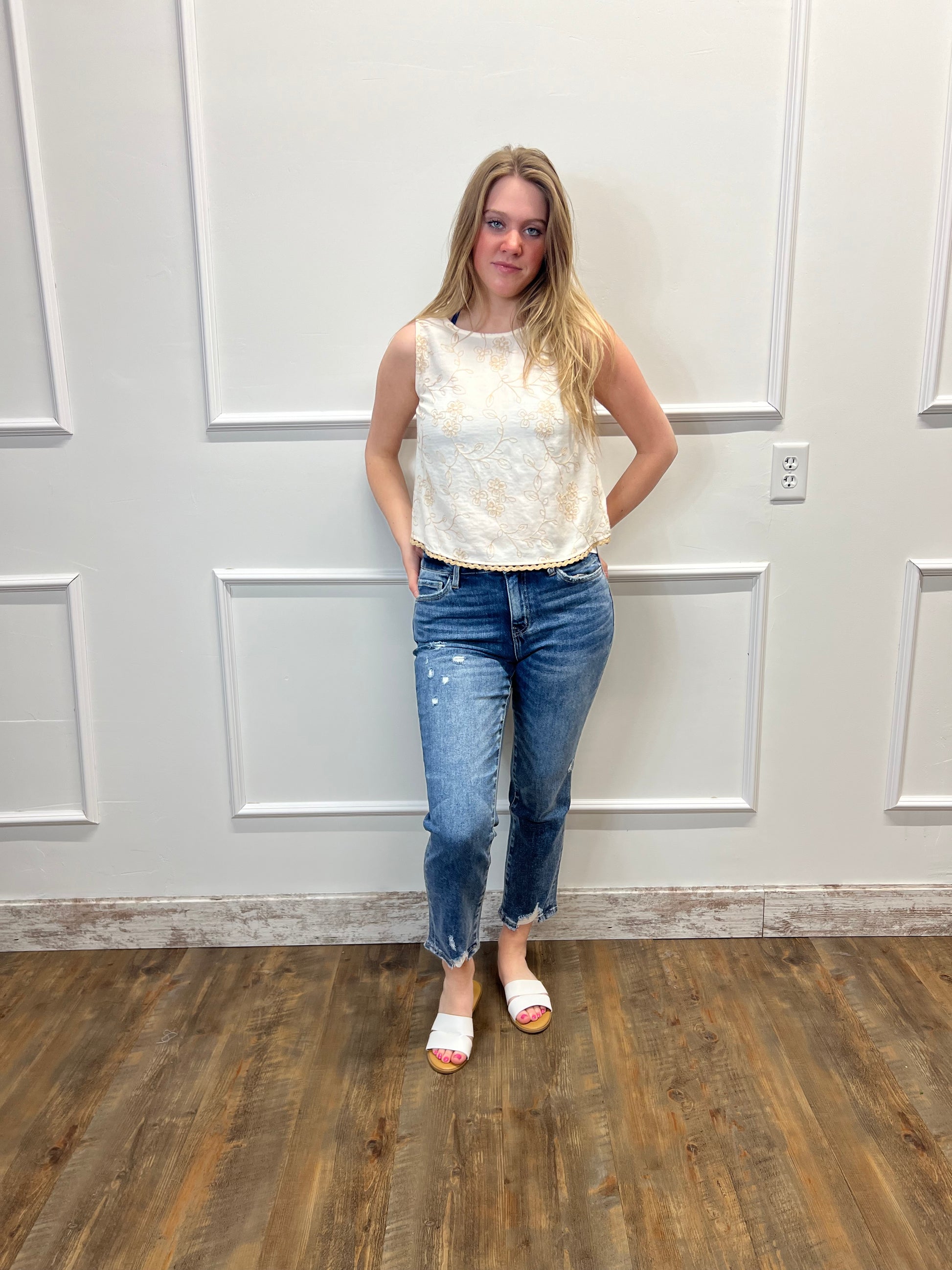 Woman standing in a room with wooden flooring and white walls.