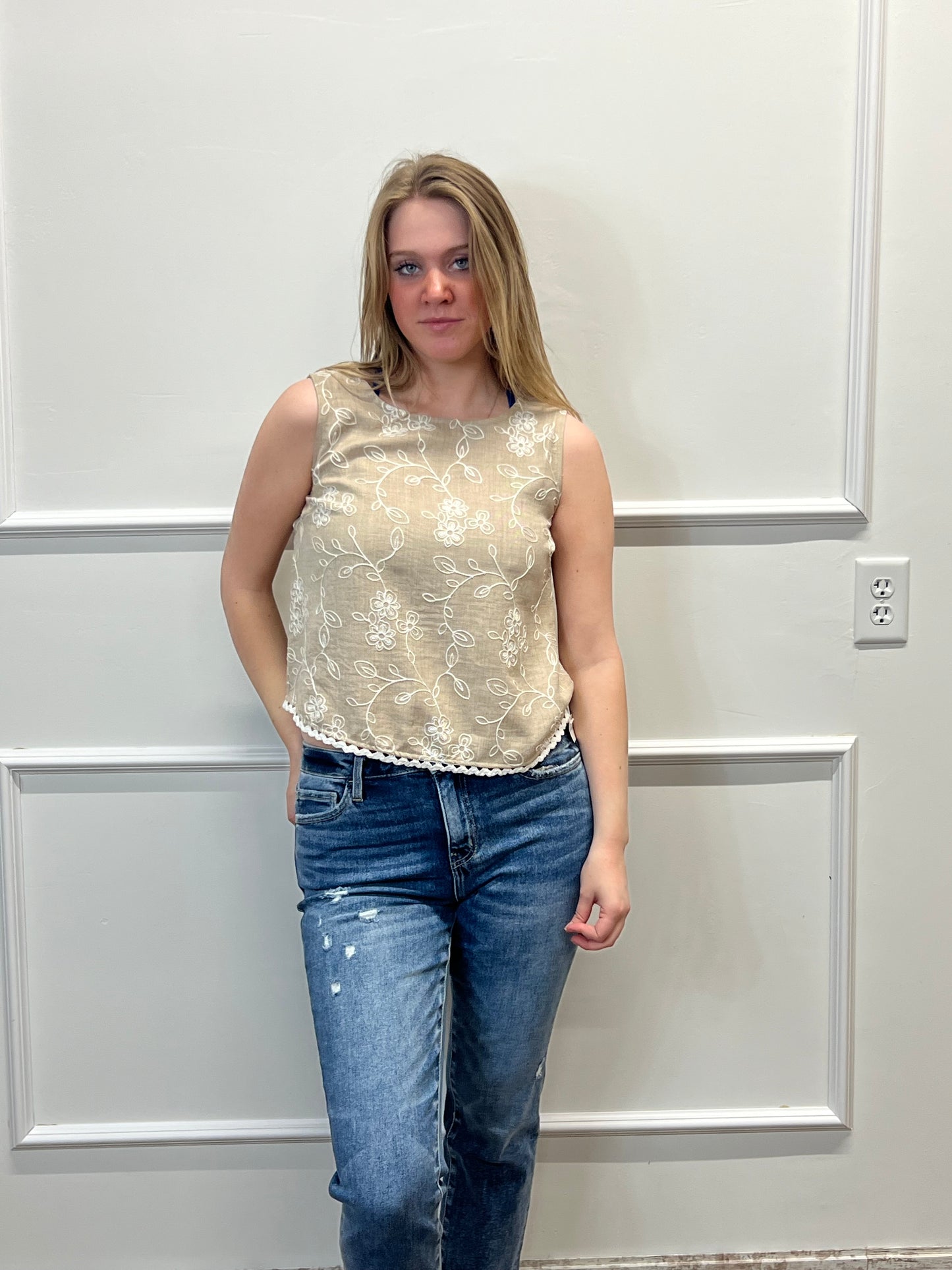 Person wearing a gold sequin top and blue jeans against a white door background