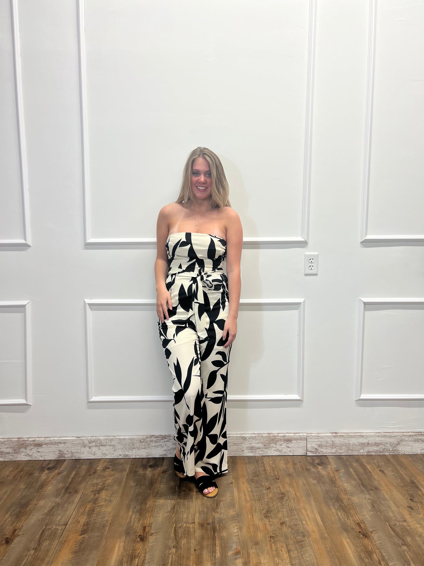 Woman wearing a black and white patterned dress standing in front of a white door.