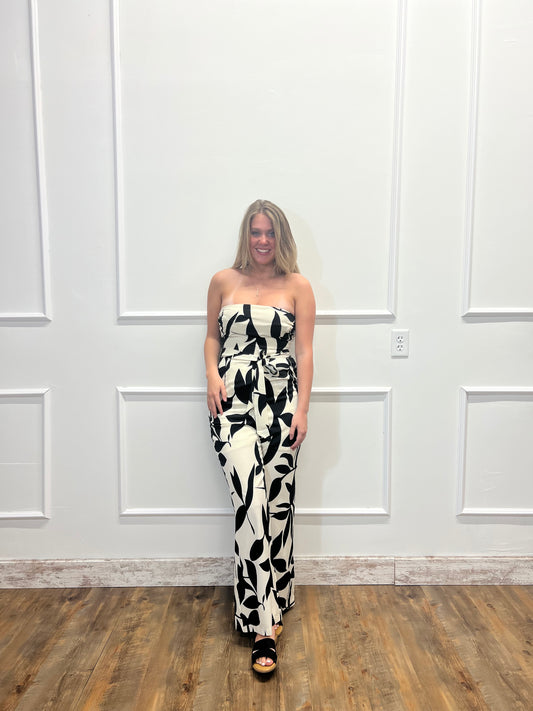 Person wearing a black and white patterned dress standing in front of a white door.