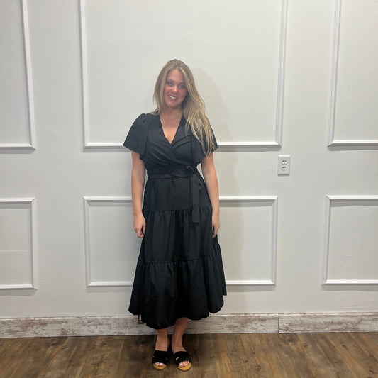 Woman in a black dress standing in front of a white paneled door.