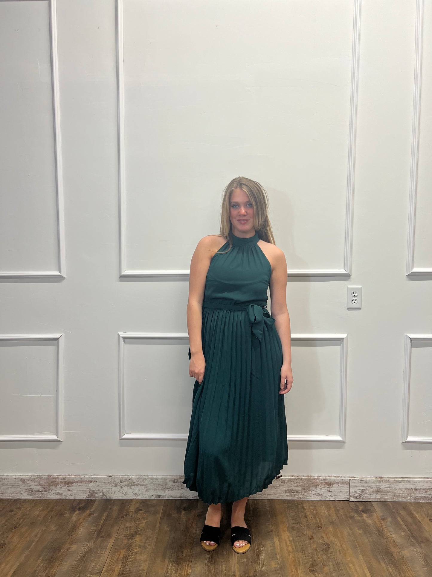 Woman in a green dress standing in front of a white door.