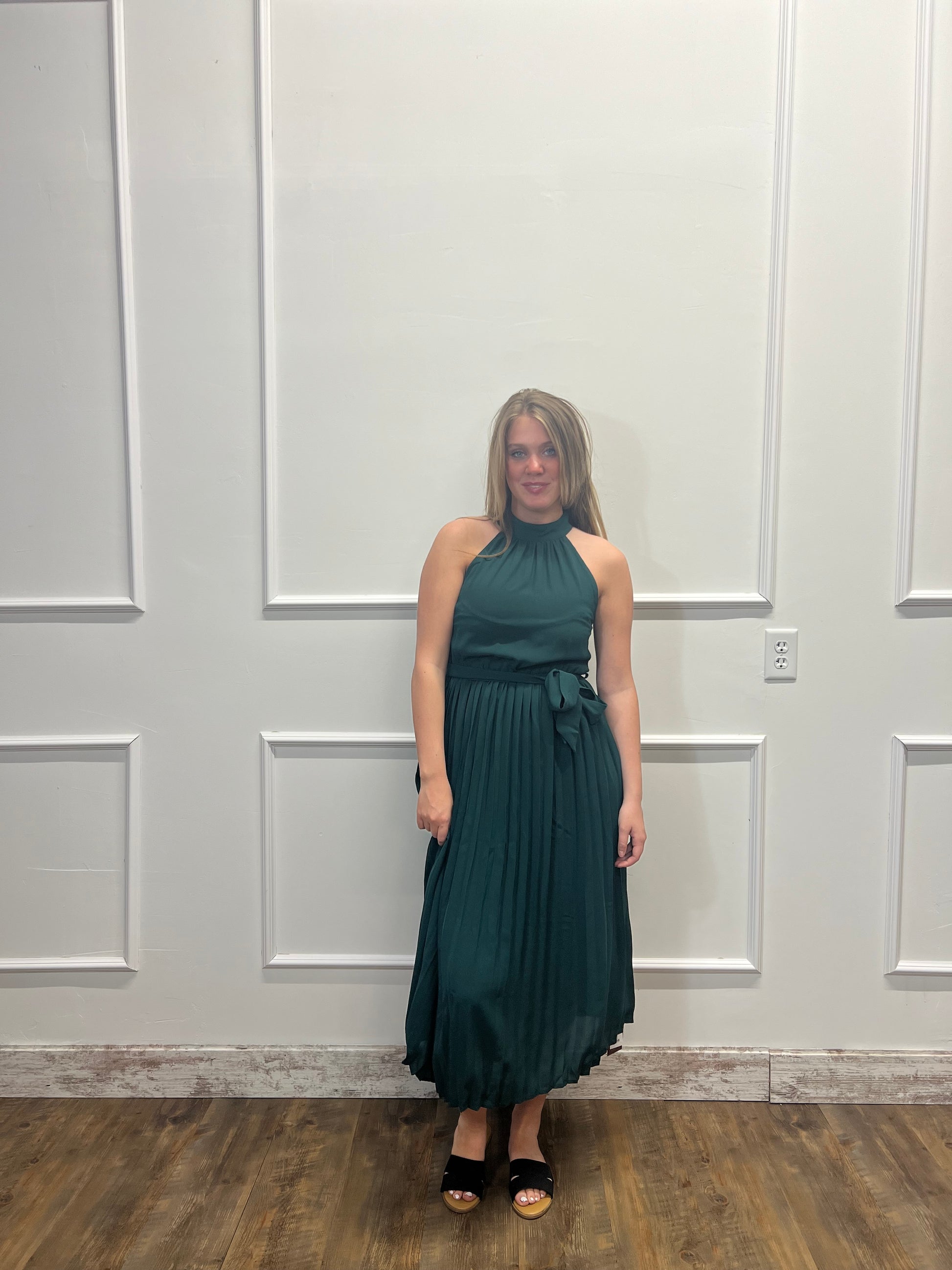 Woman in a green dress standing in front of a white door.