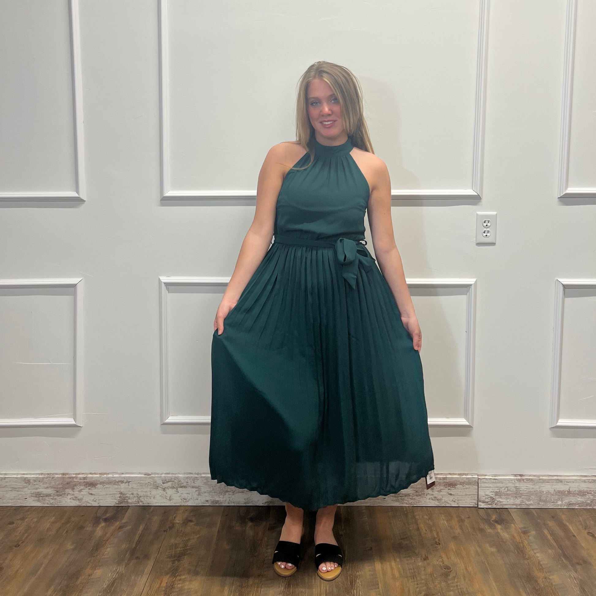 Woman in a green dress standing in front of a white paneled door.