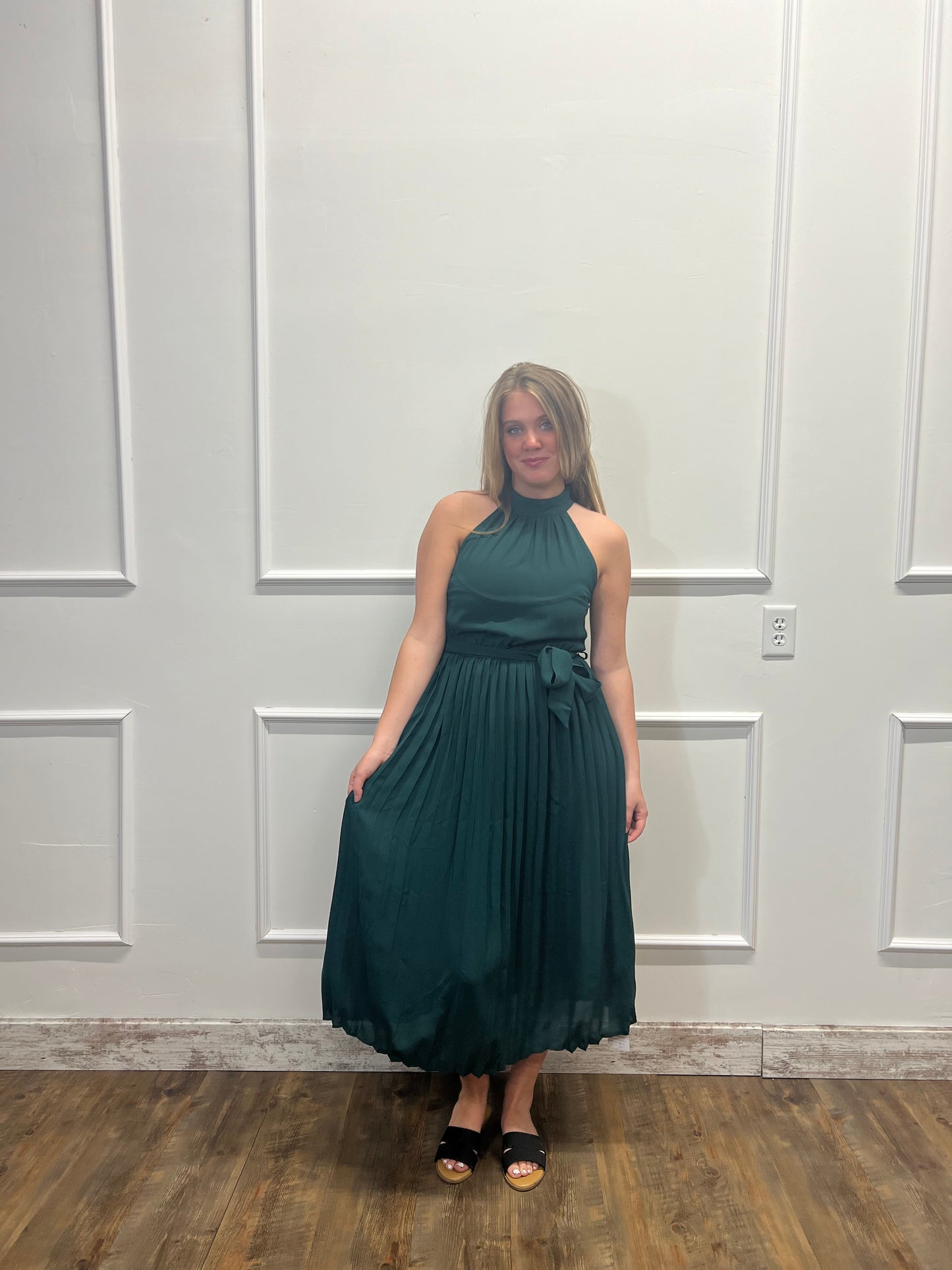 Woman in a teal dress standing in front of a white paneled door.