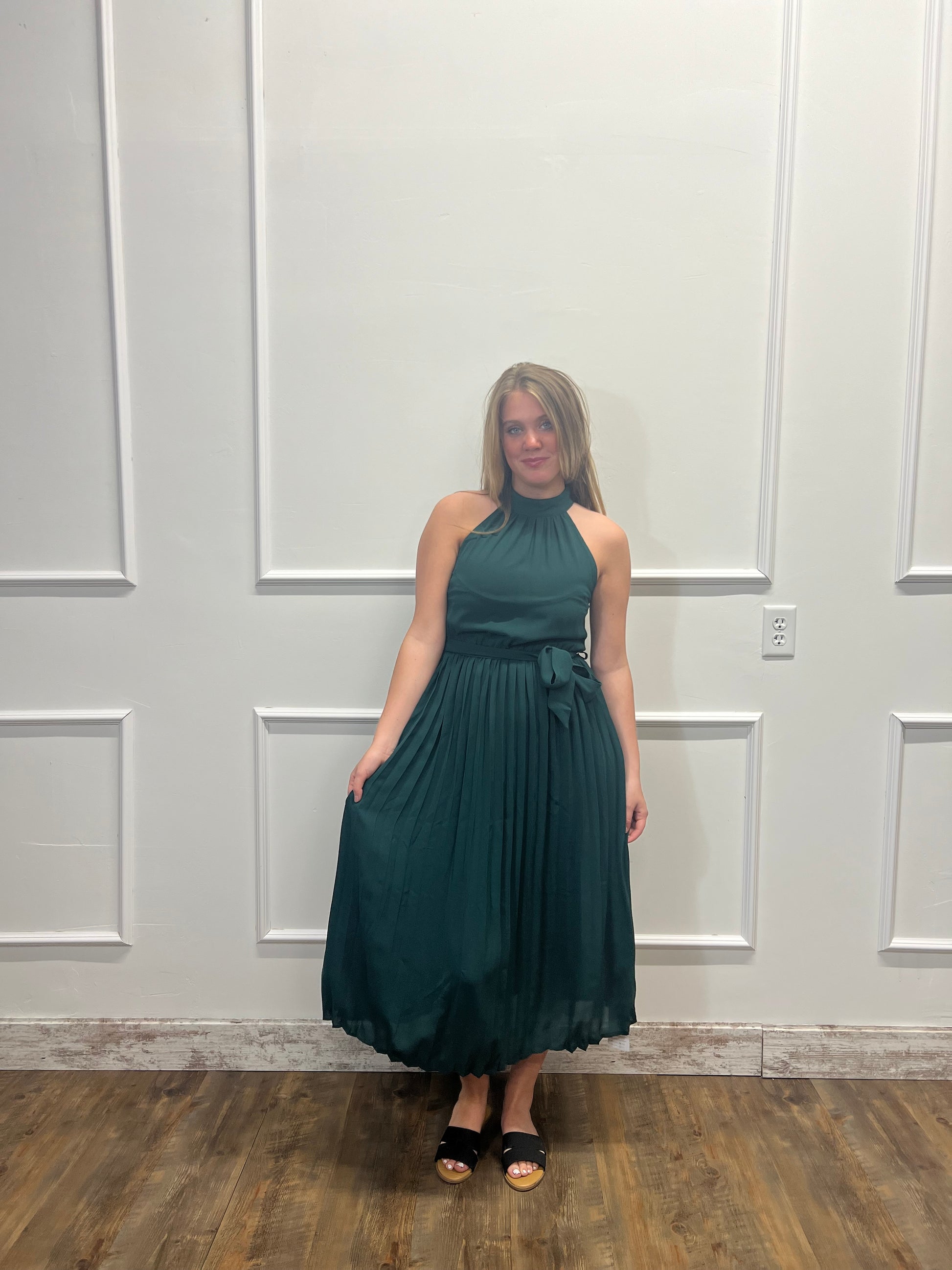 Woman in a teal dress standing in front of a white paneled door.