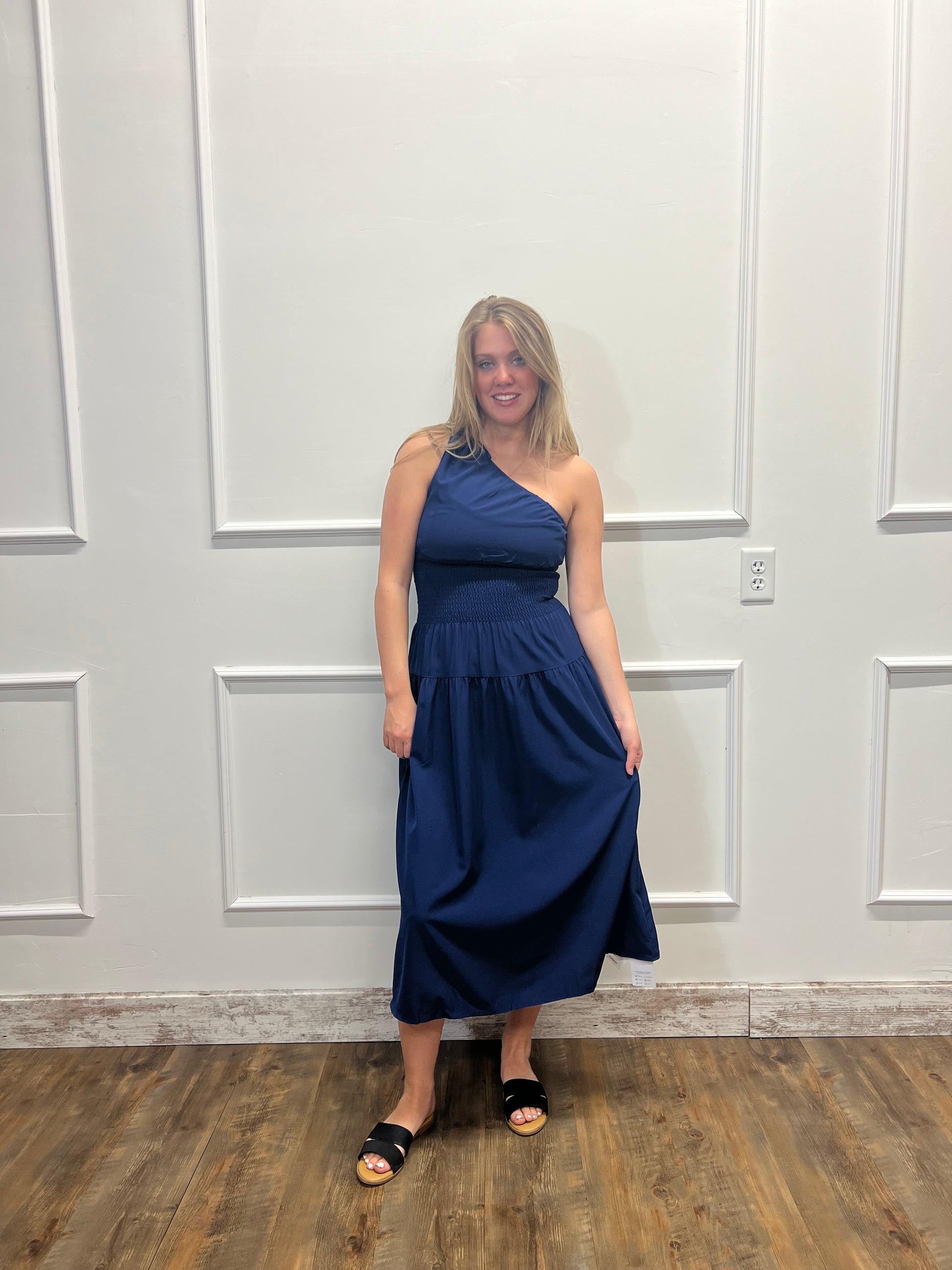 Woman in a blue dress standing in front of a white paneled door.