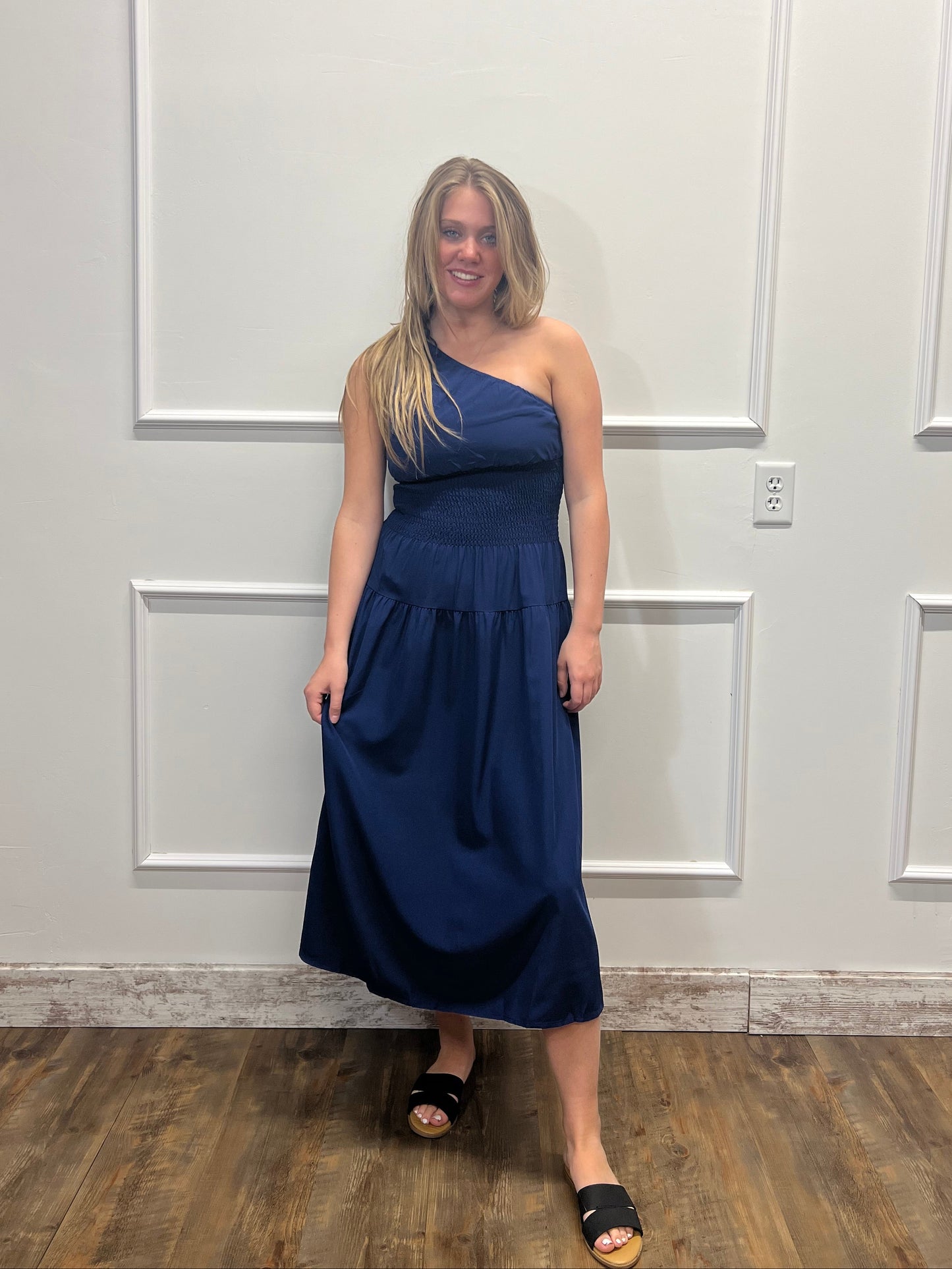 Woman in a blue dress standing in front of a white paneled door.
