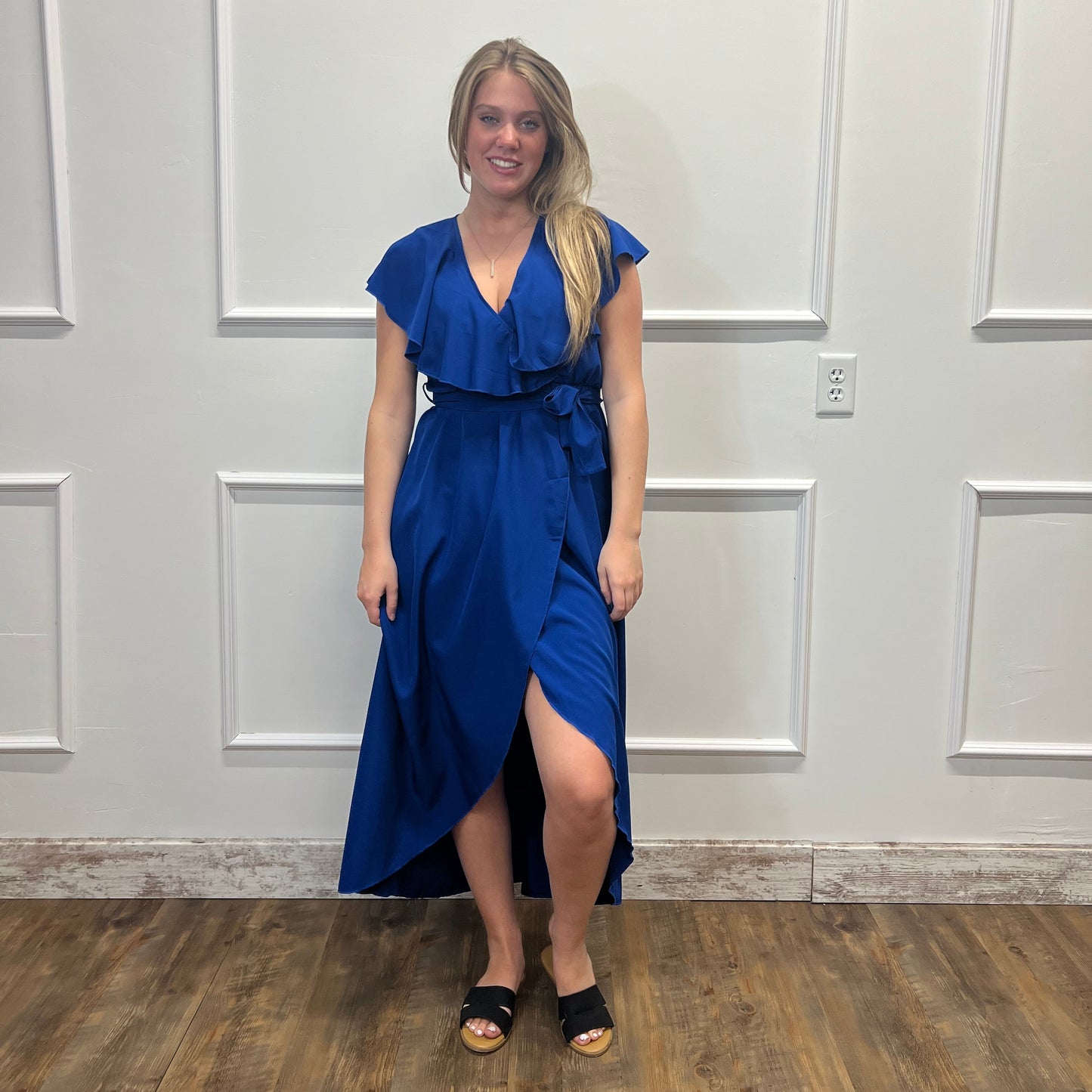 Woman in a blue dress standing in front of a white paneled door.