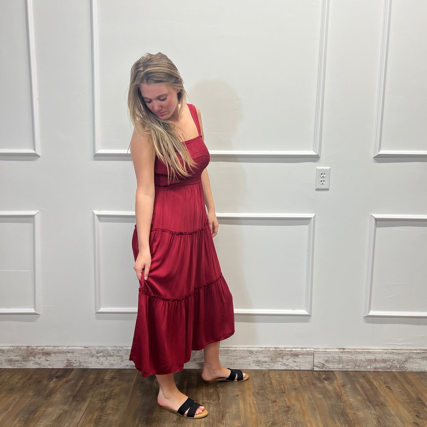 Woman wearing a red dress standing against a white paneled wall.