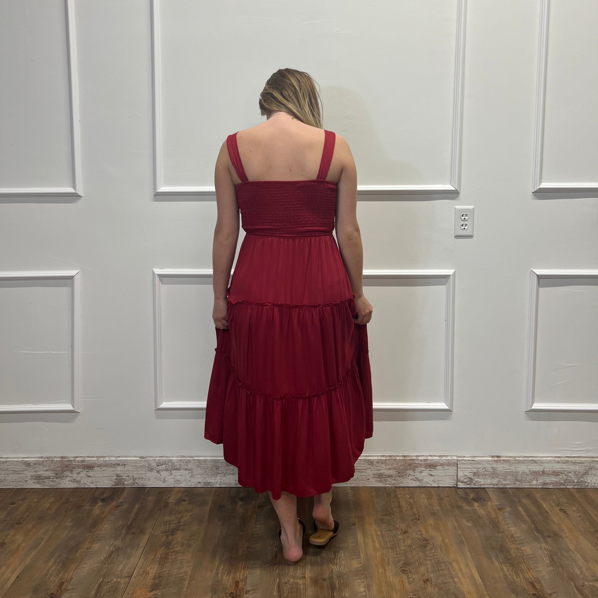 Person wearing a red dress standing in front of a white door.