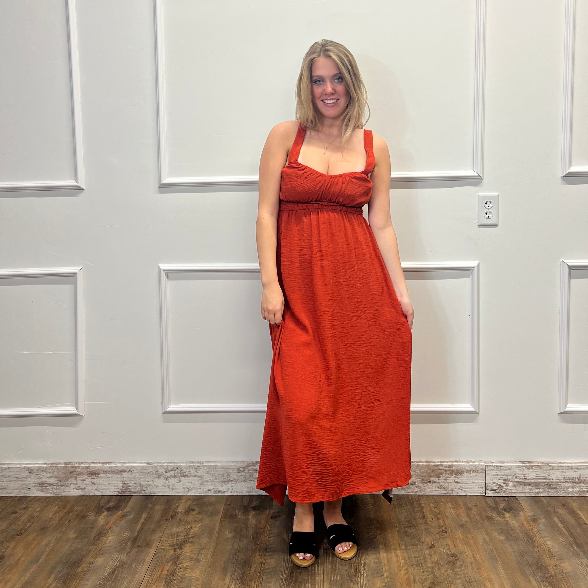 Person wearing a red dress standing in front of a white door.