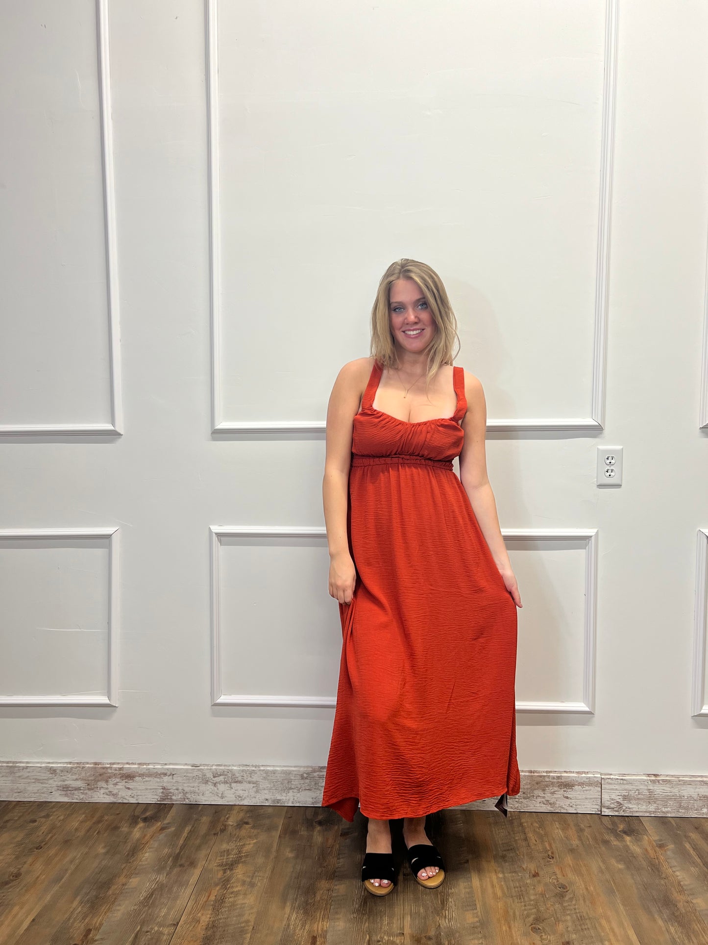 Person wearing a red dress standing in front of a white door.