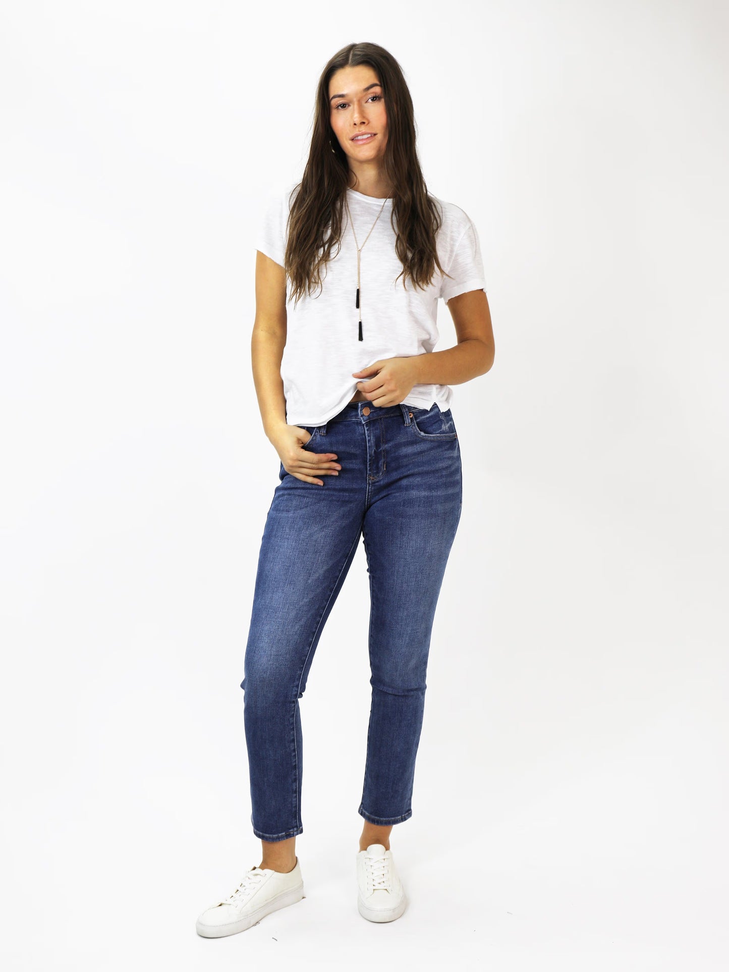 Woman wearing a white t-shirt and blue jeans on a white background