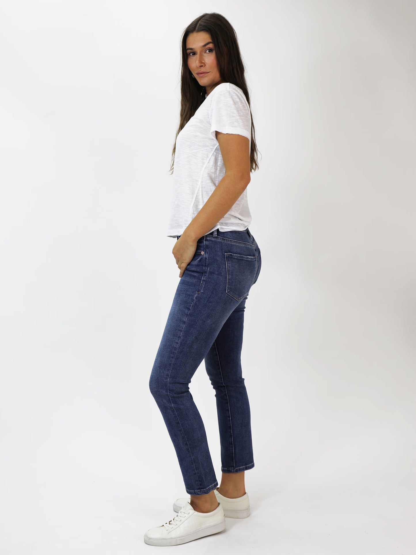 Woman wearing a white t-shirt and blue jeans on a white background