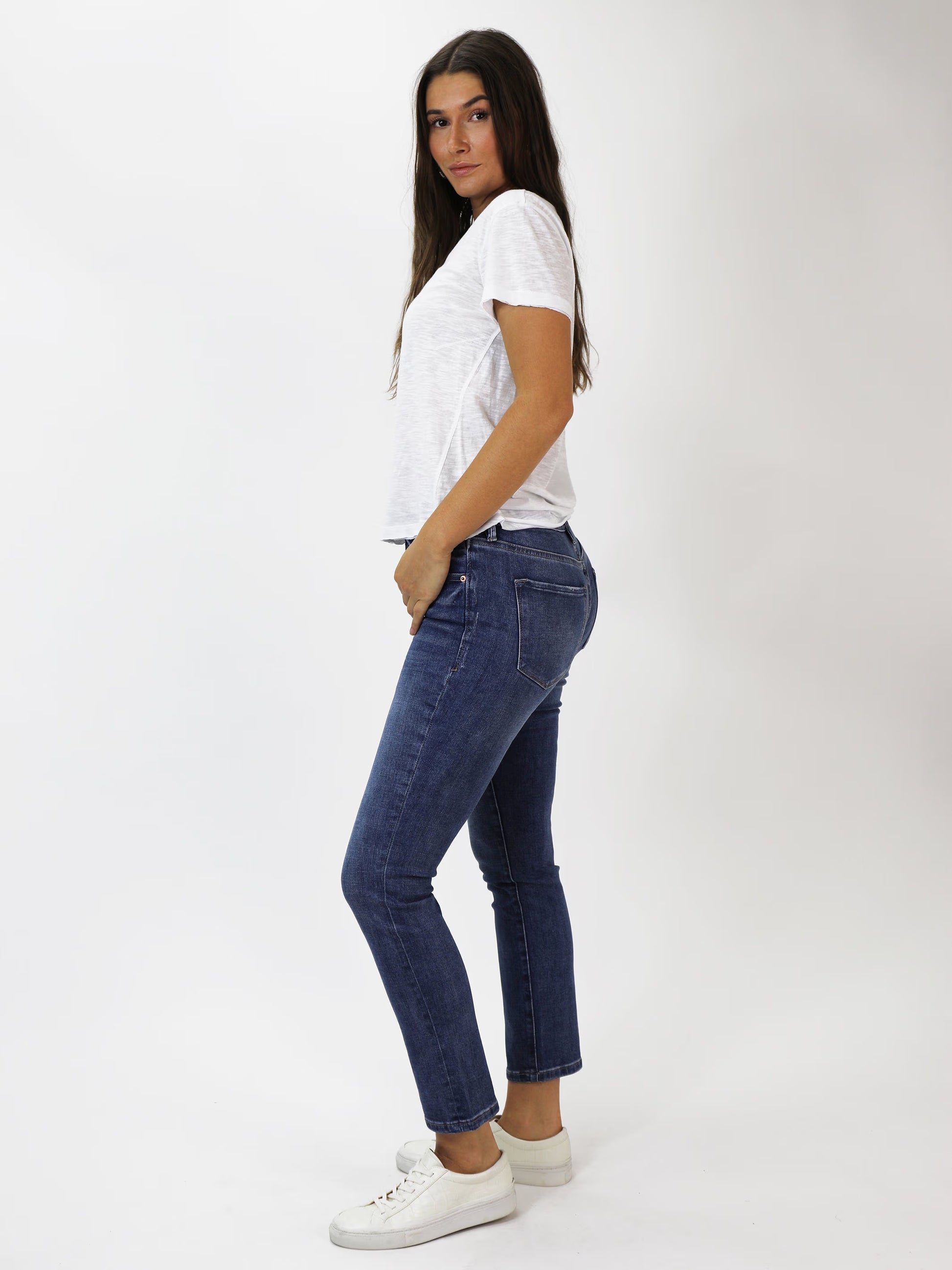 Woman wearing a white t-shirt and blue jeans on a white background