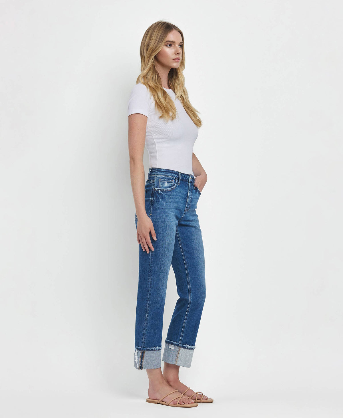 Woman wearing blue jeans and a white top on a white background