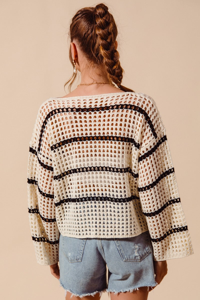 Woman wearing a black and white patterned top with denim shorts on a beige background