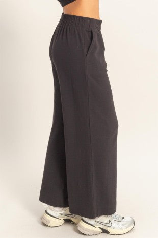 Black wide-leg pants worn by a person on a light beige background