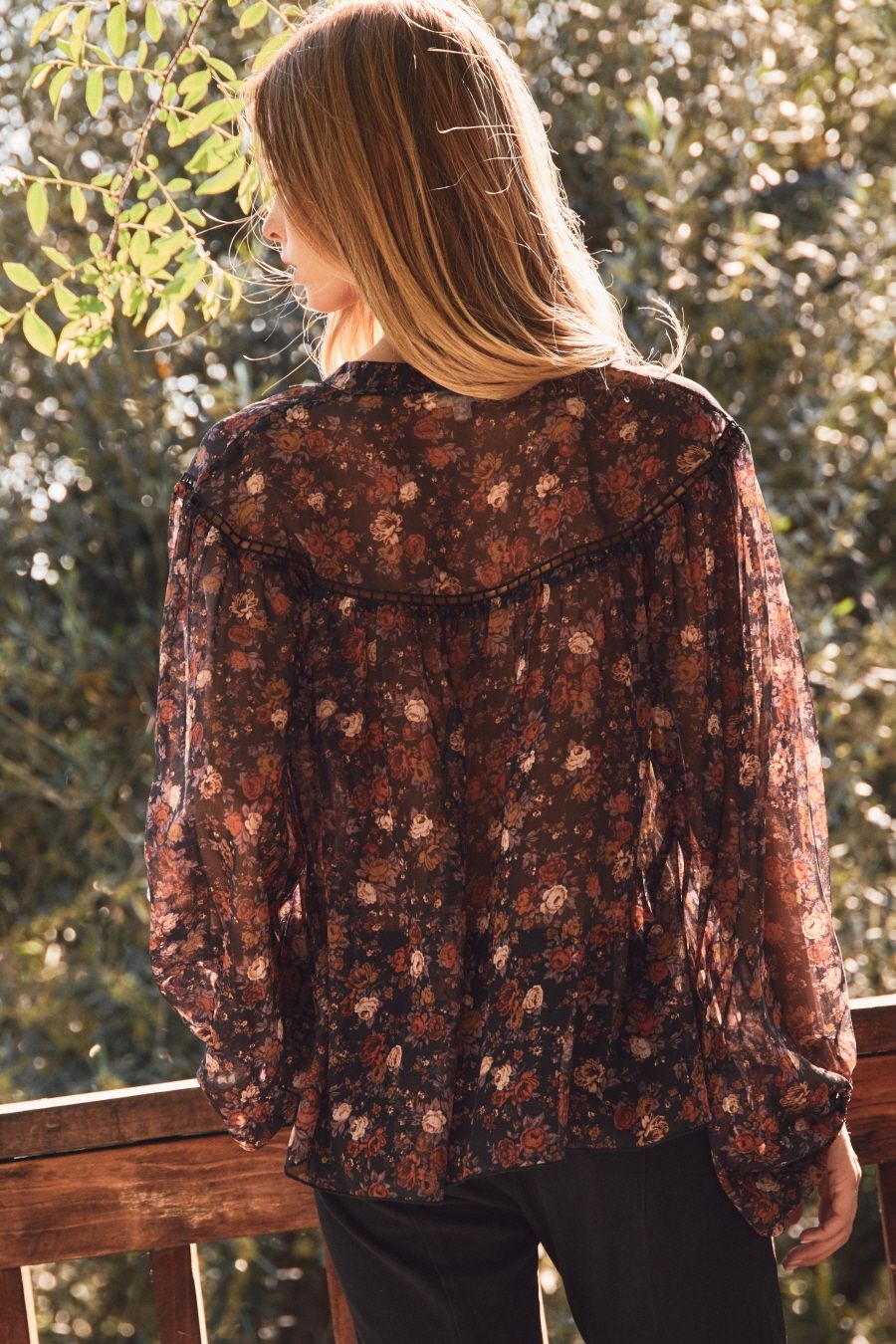 Person wearing a floral blouse with a blurred natural background