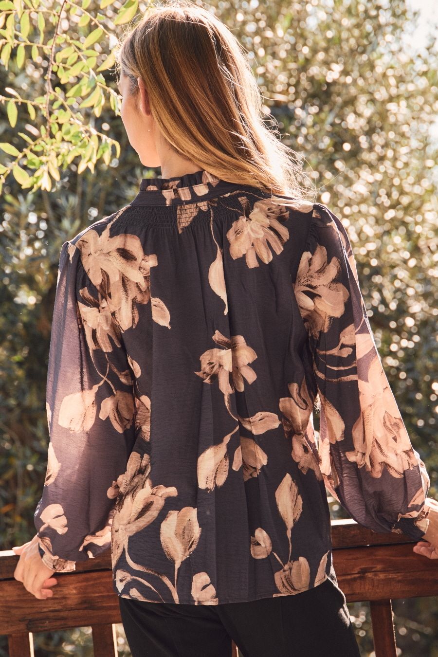 Person wearing a floral blouse with a blurred natural background