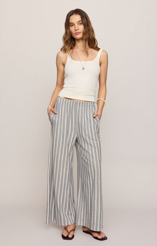 Woman wearing a white tank top and striped pants on a plain background