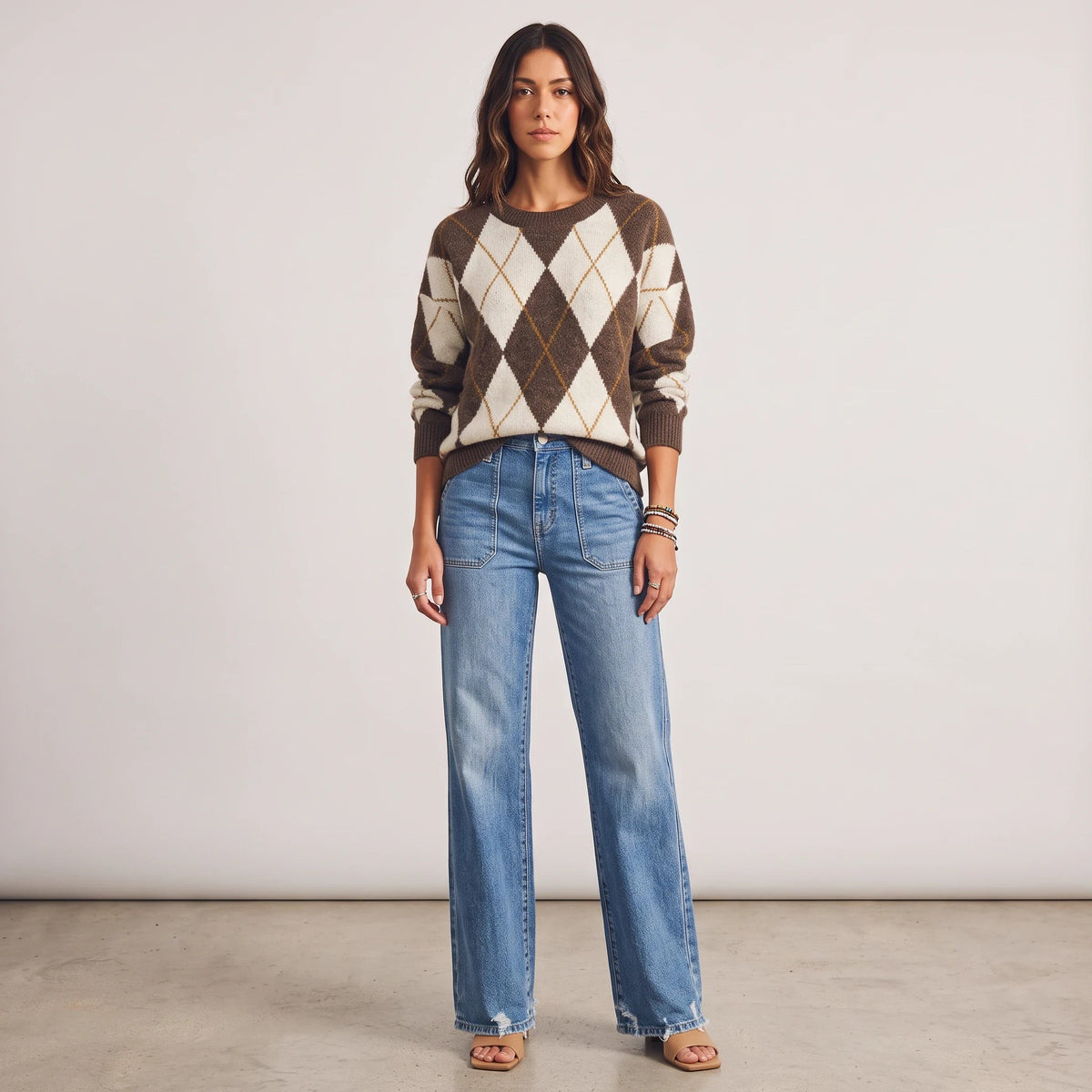 Model wearing Apricot Lane Duluth brown and cream argyle knit sweater with blue wide-leg denim jeans