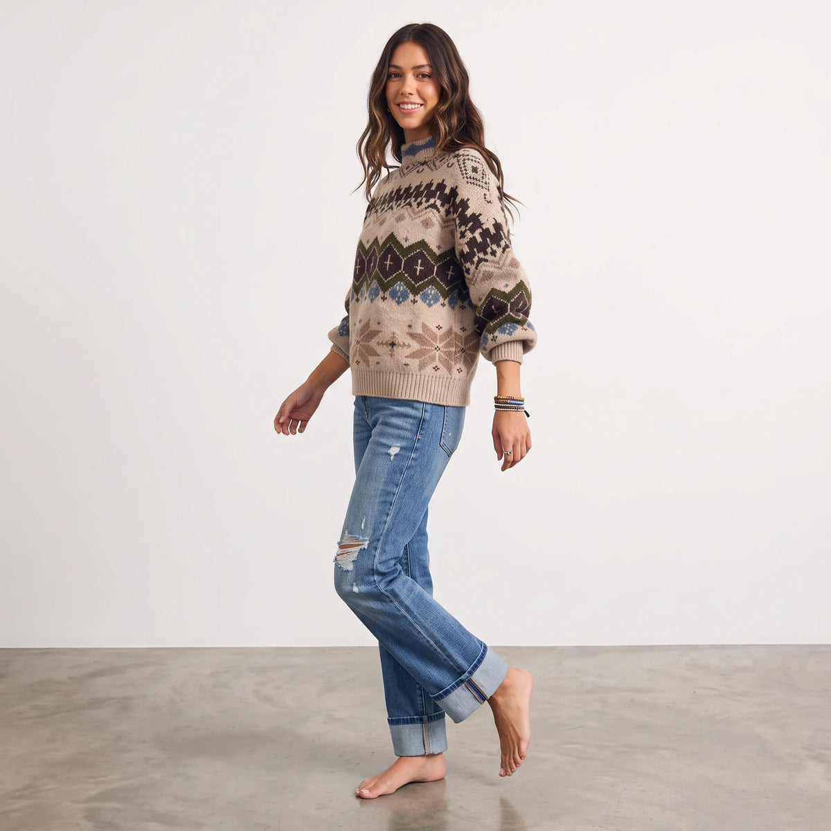 Apricot Lane Duluth Aspen Fair Isle mock neck sweater with winter motifs, worn by a smiling model with blue jeans.