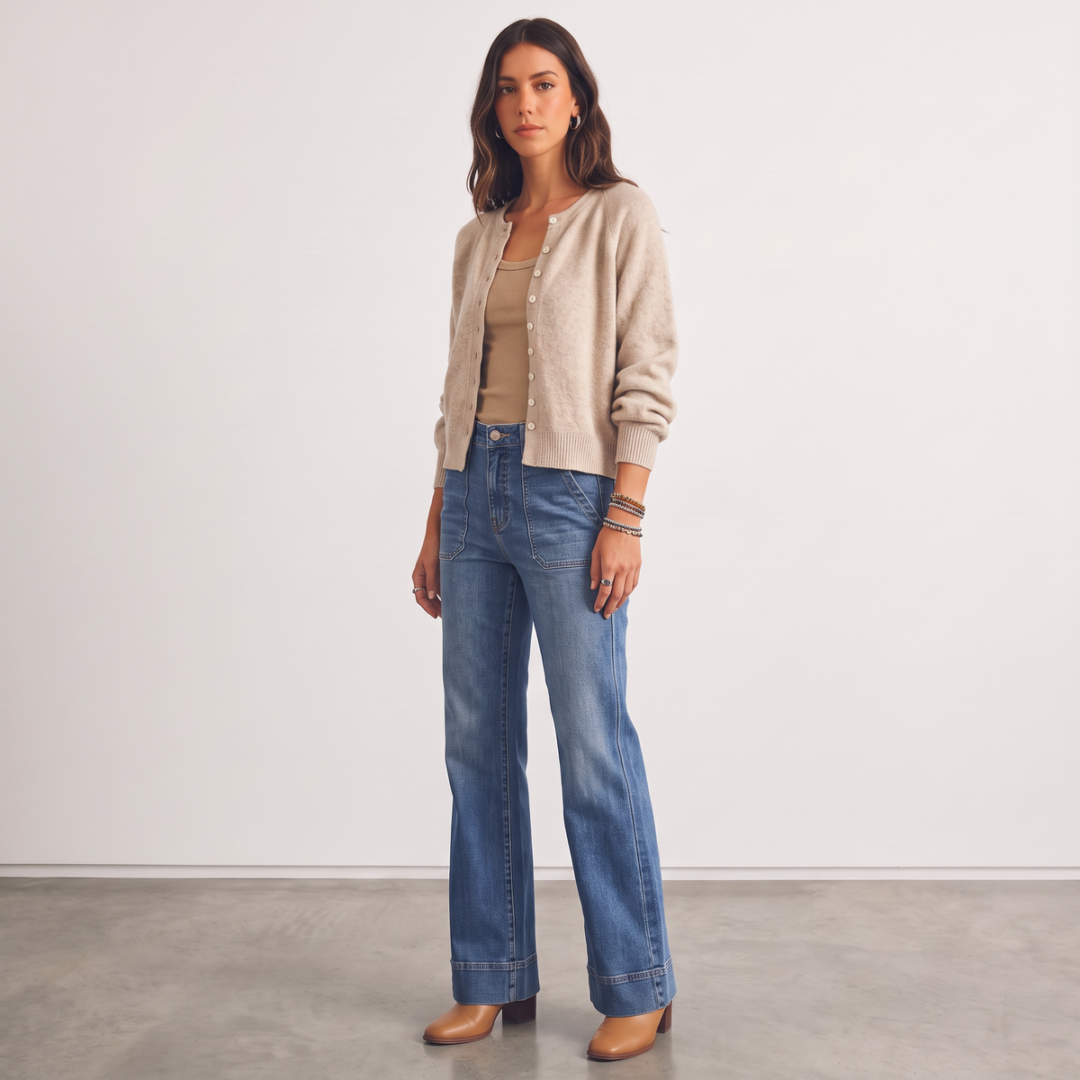 Model wearing Apricot Lane Duluth beige button-front knit cardigan with blue wide-leg jeans and tan boots