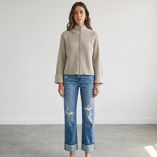 Model wearing Apricot Lane Duluth beige textured zip-up knit cardigan with long sleeves and blue distressed denim jeans