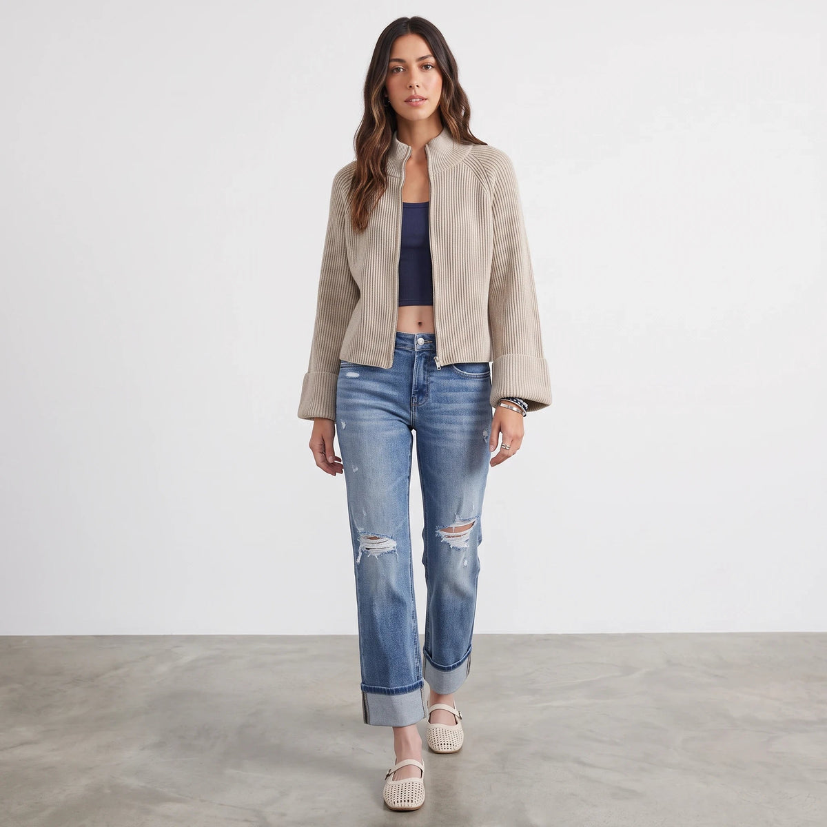 Model wearing Apricot Lane Duluth Avery beige textured zip-up knit cardigan with blue jeans and cream shoes
