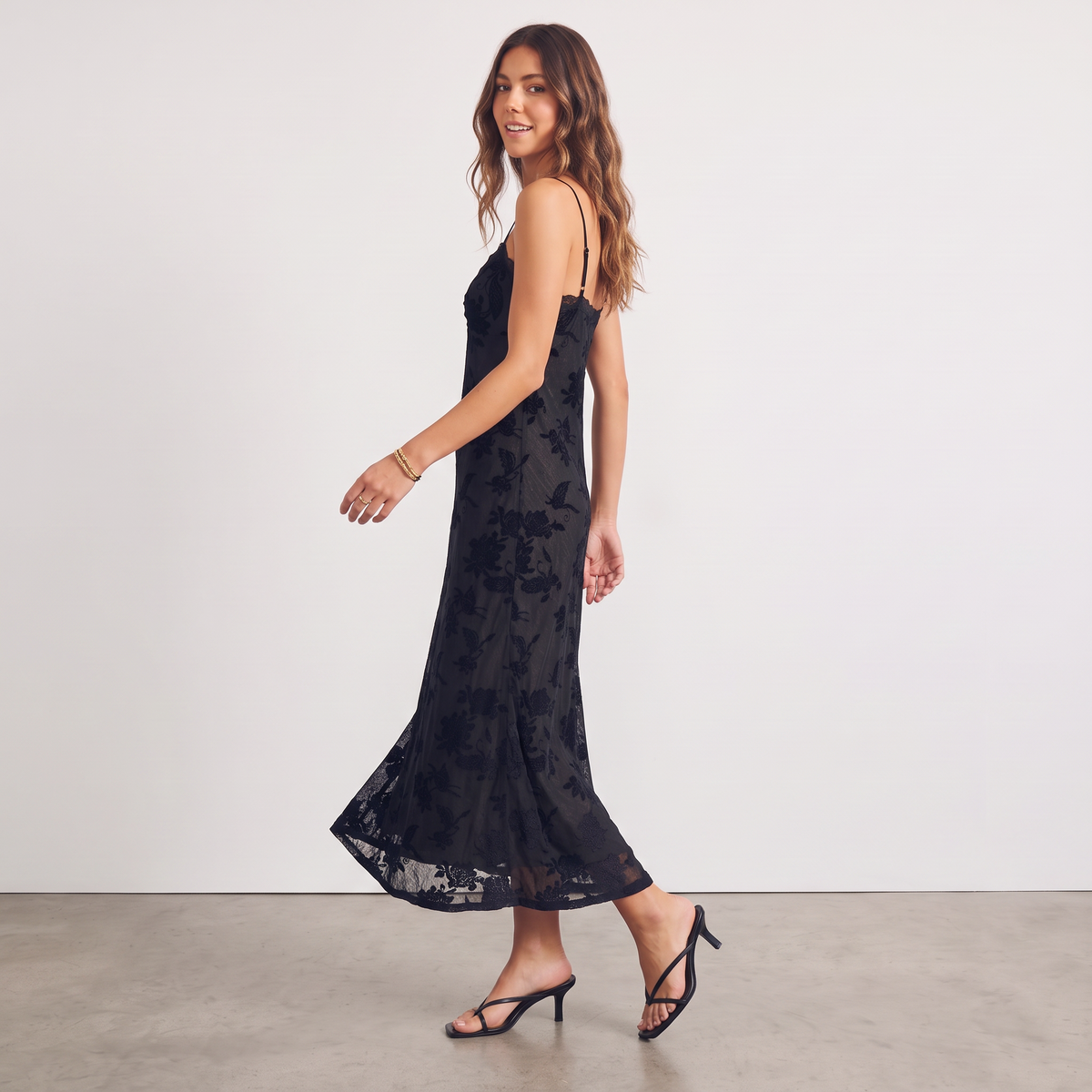 Model wearing Apricot Lane Duluth black floral velvet burnout midi slip dress with scalloped lace hem and thin straps.