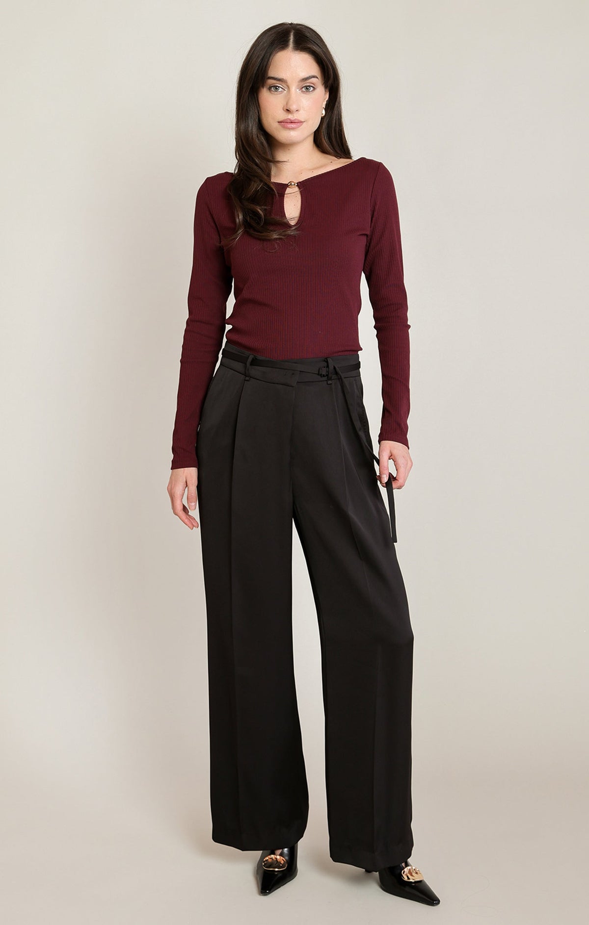 Model wearing Apricot Lane Duluth Simone satin belted pants in black with a burgundy long-sleeve top and black heels.