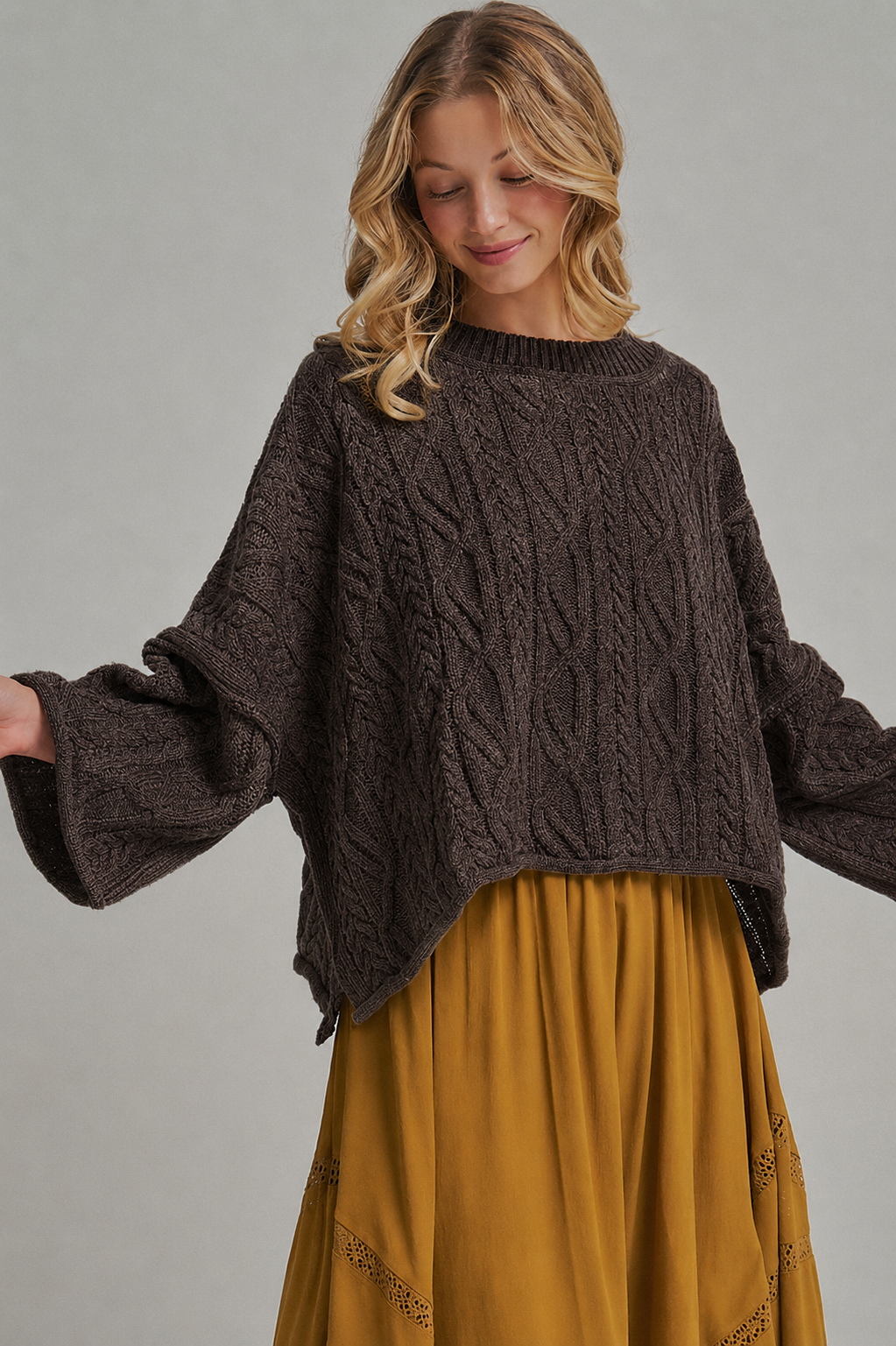 A model wears the Apricot Lane Duluth Isla oversized dark brown cable knit sweater with long sleeves and a relaxed fit.