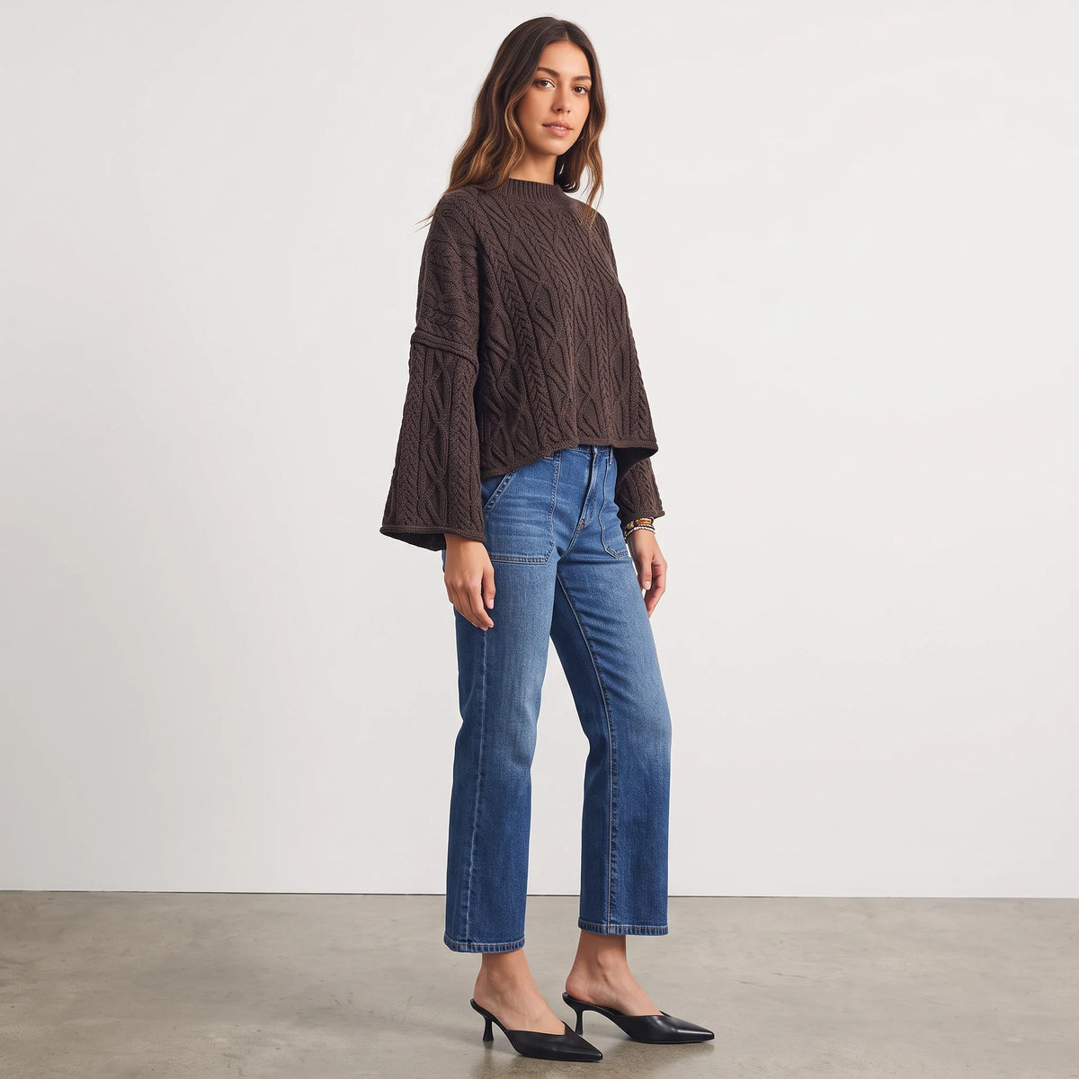 Apricot Lane Duluth model wearing a brown oversized cable knit sweater with wide sleeves paired with blue jeans